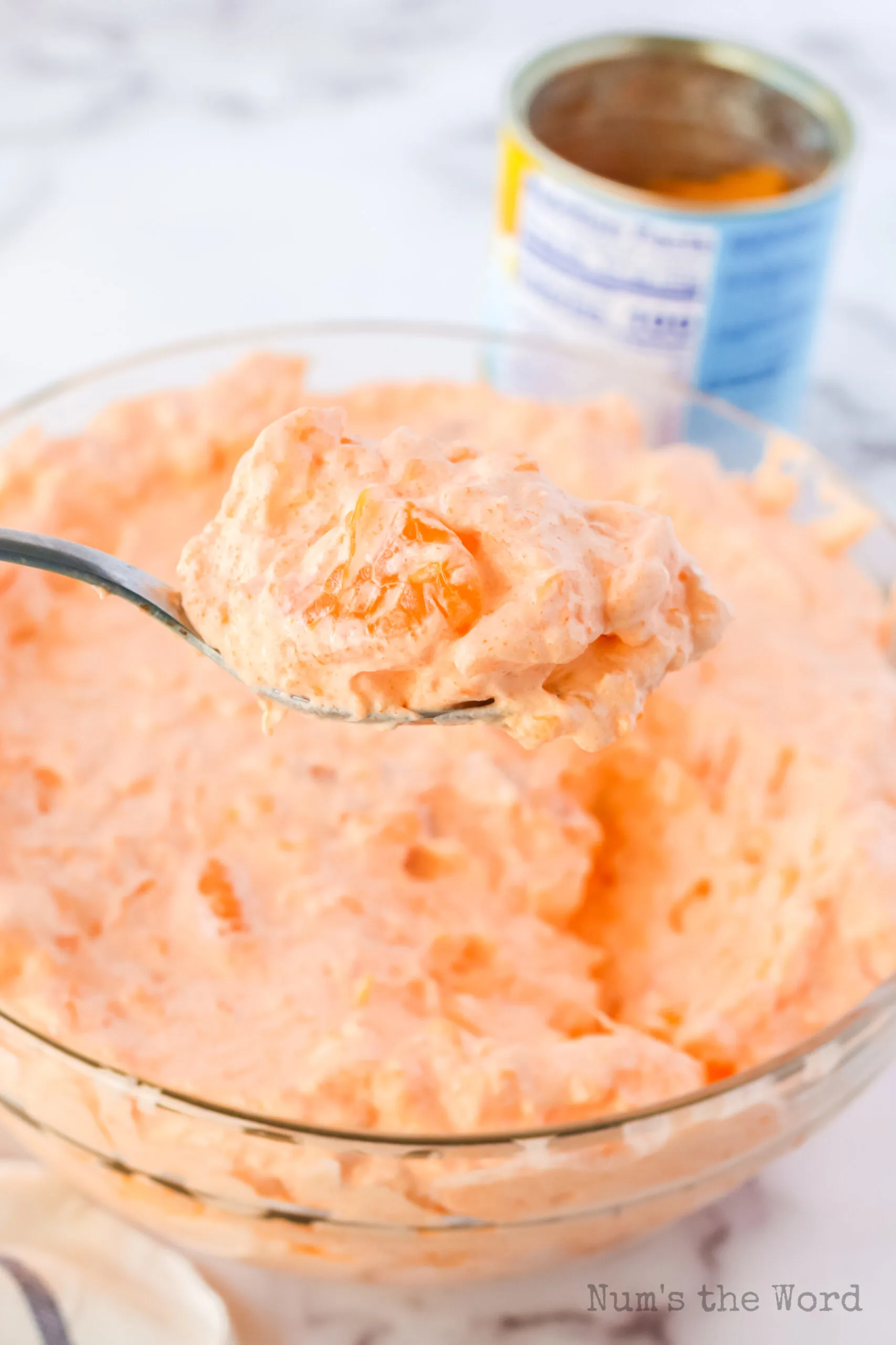 prepared orange fluff in bowl with a spoon scooping a portion out