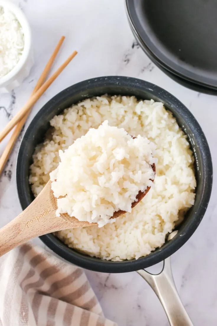 wooden spoon scooping out a portion of coconut jasmine rice from pot