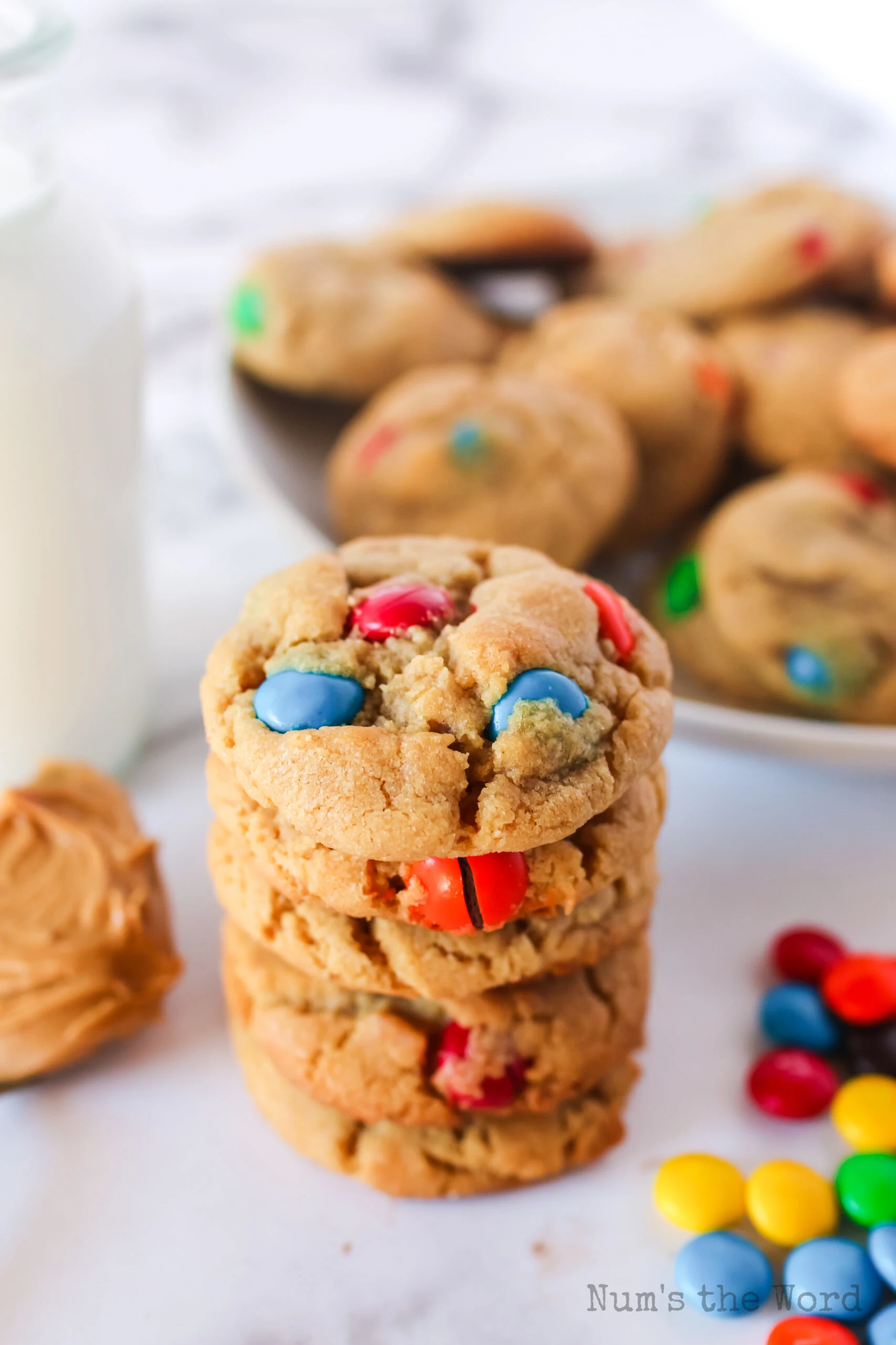 4 cookies stacked up on top of each other with a plate of cookies in the background.