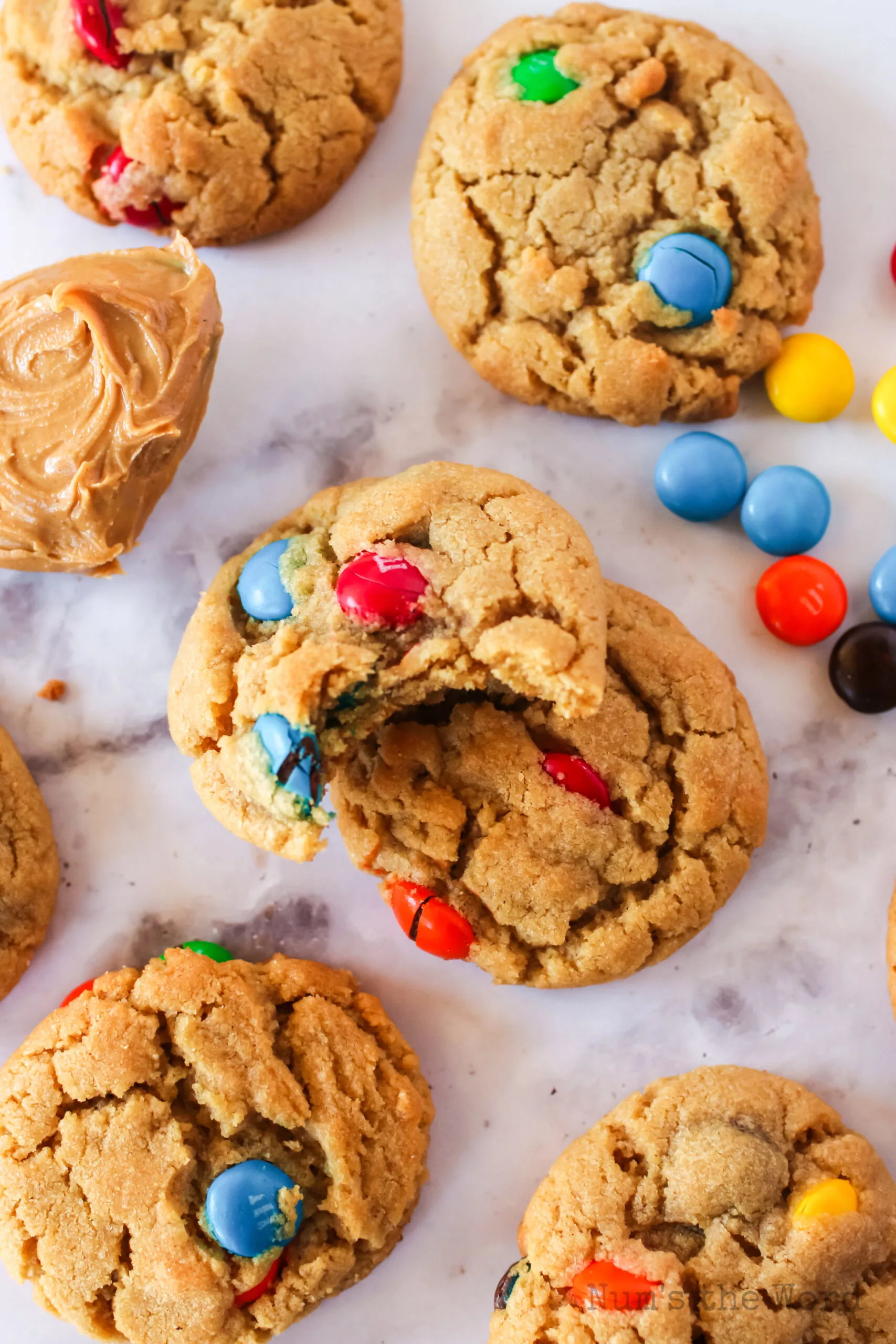 cookies laid out on counter with a peanut butter spoon and a bite removed from one cookie.