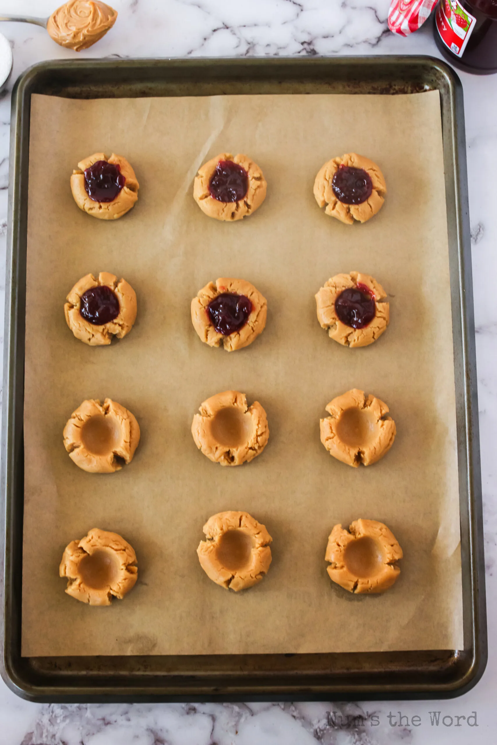 6 dough balls indented and 6 dough balls indented with Jelly dropped inside the indent.