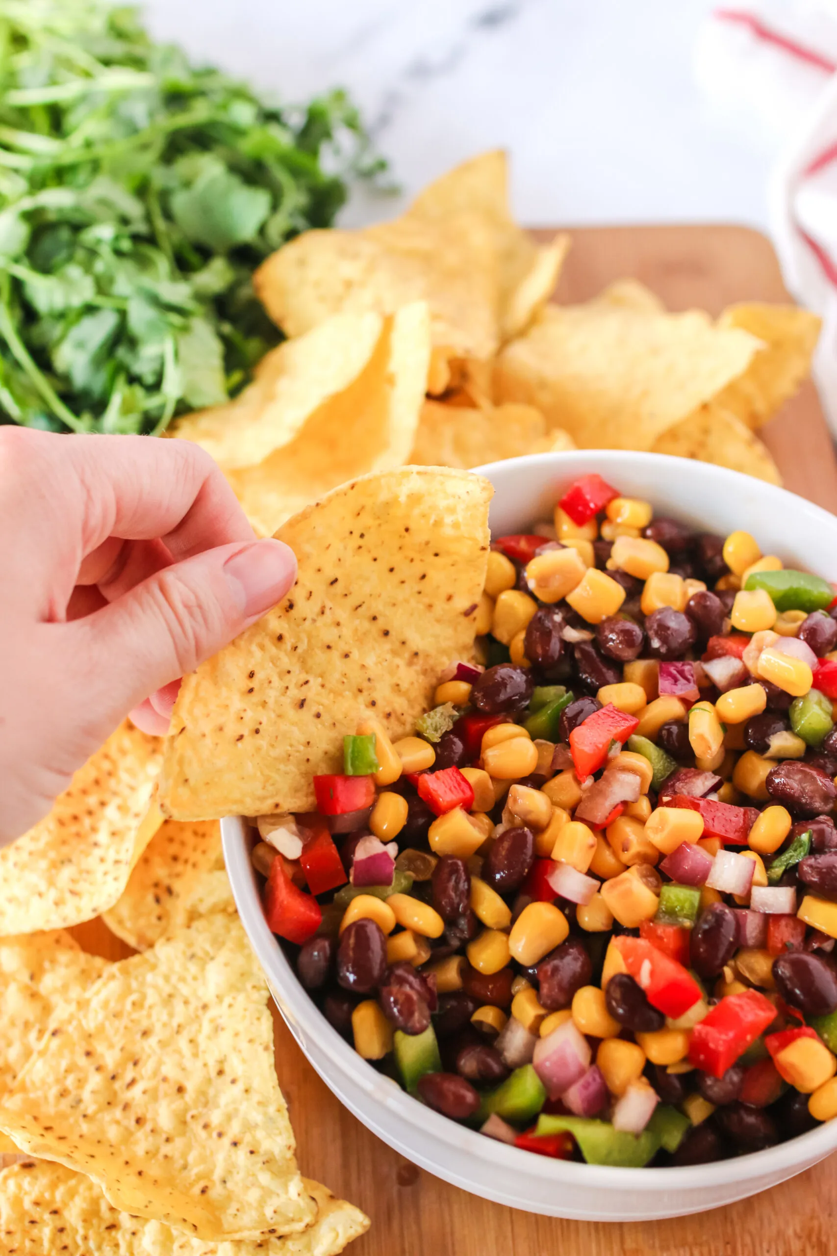 hand dipping a tortilla chip into black bean salsa