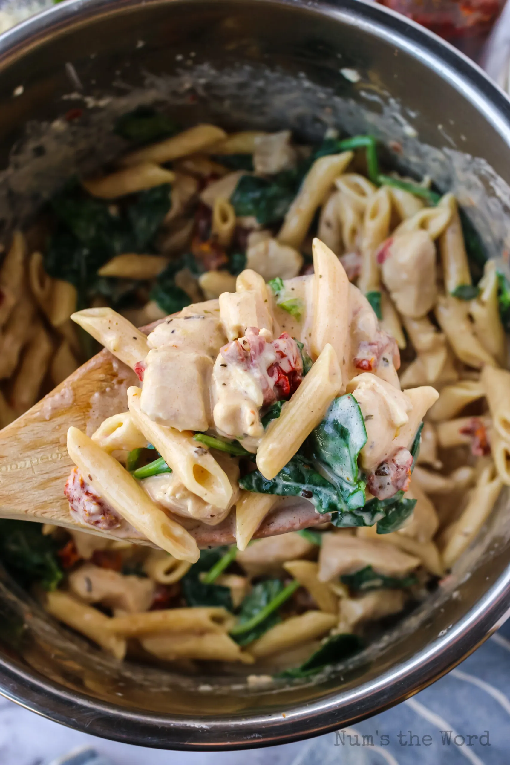 wooden spoon scooping out a portion of instant pot Tuscan chicken