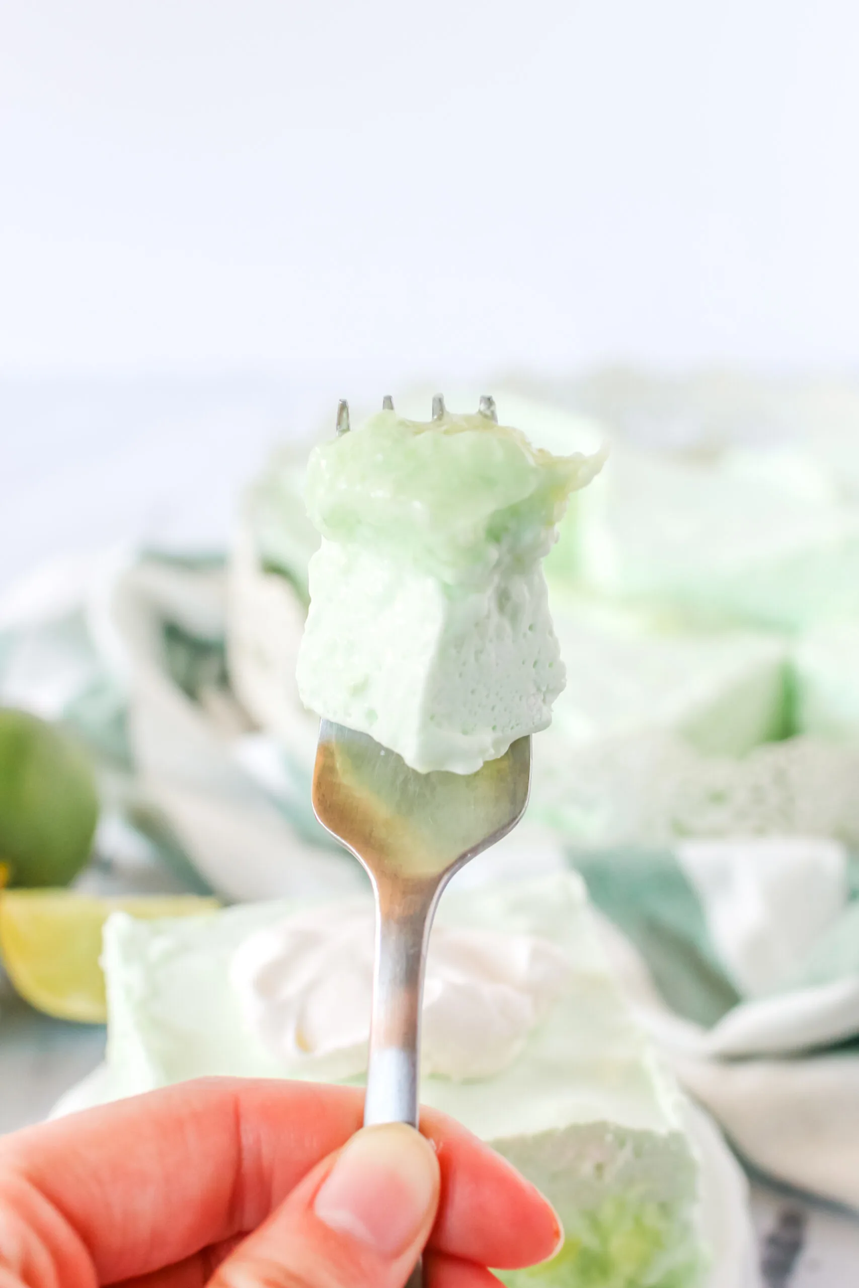 chilled and sliced jello on a plate. Fork full being held up to camera lens