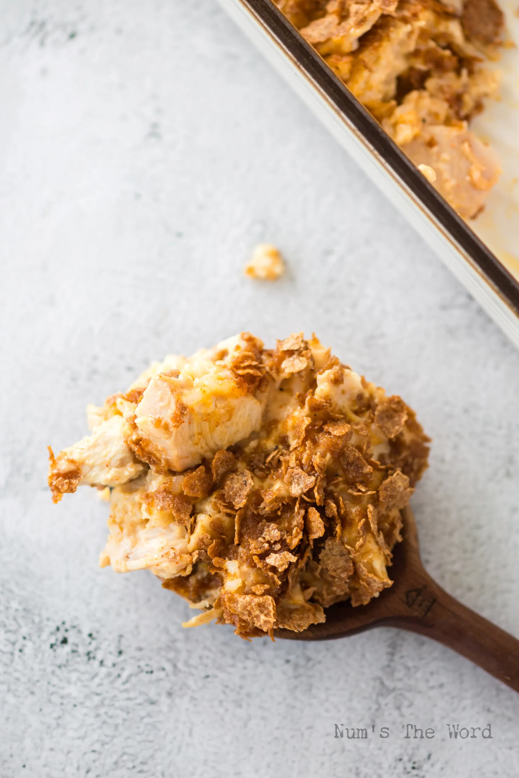 spoonful of cornflake and chicken casserole on counter next to casserole dish