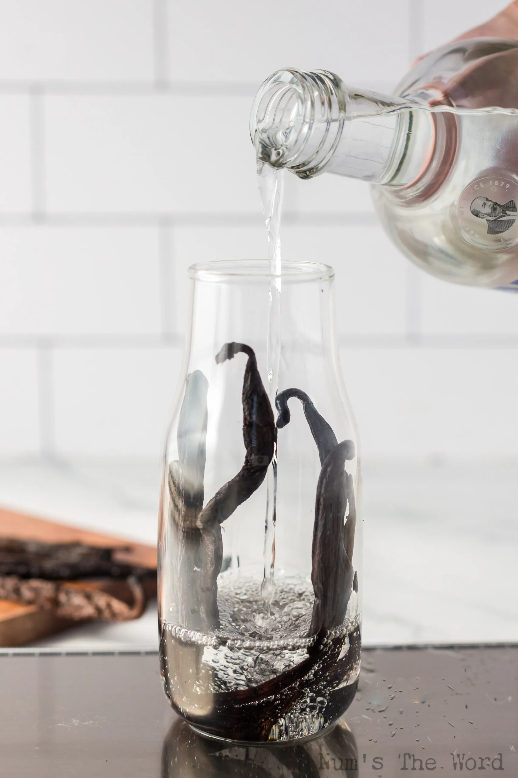 vanilla beans placed in a jar with vodka being poured over beans