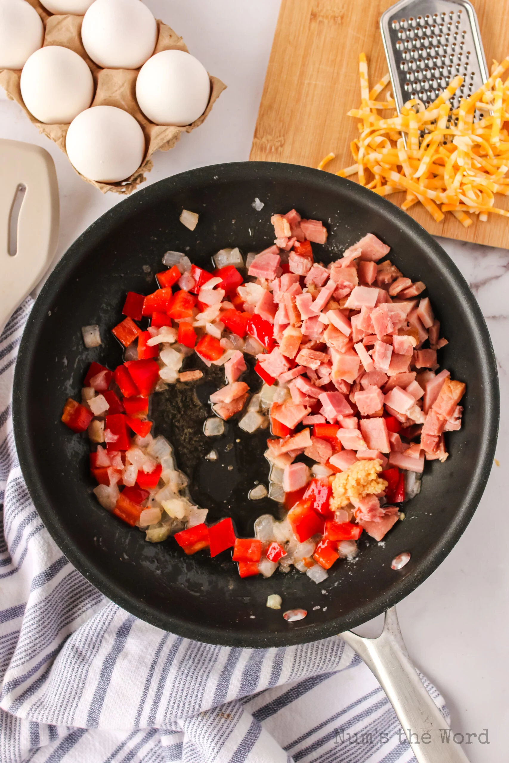 cooked bell pepper and onion in a skillet with ham added