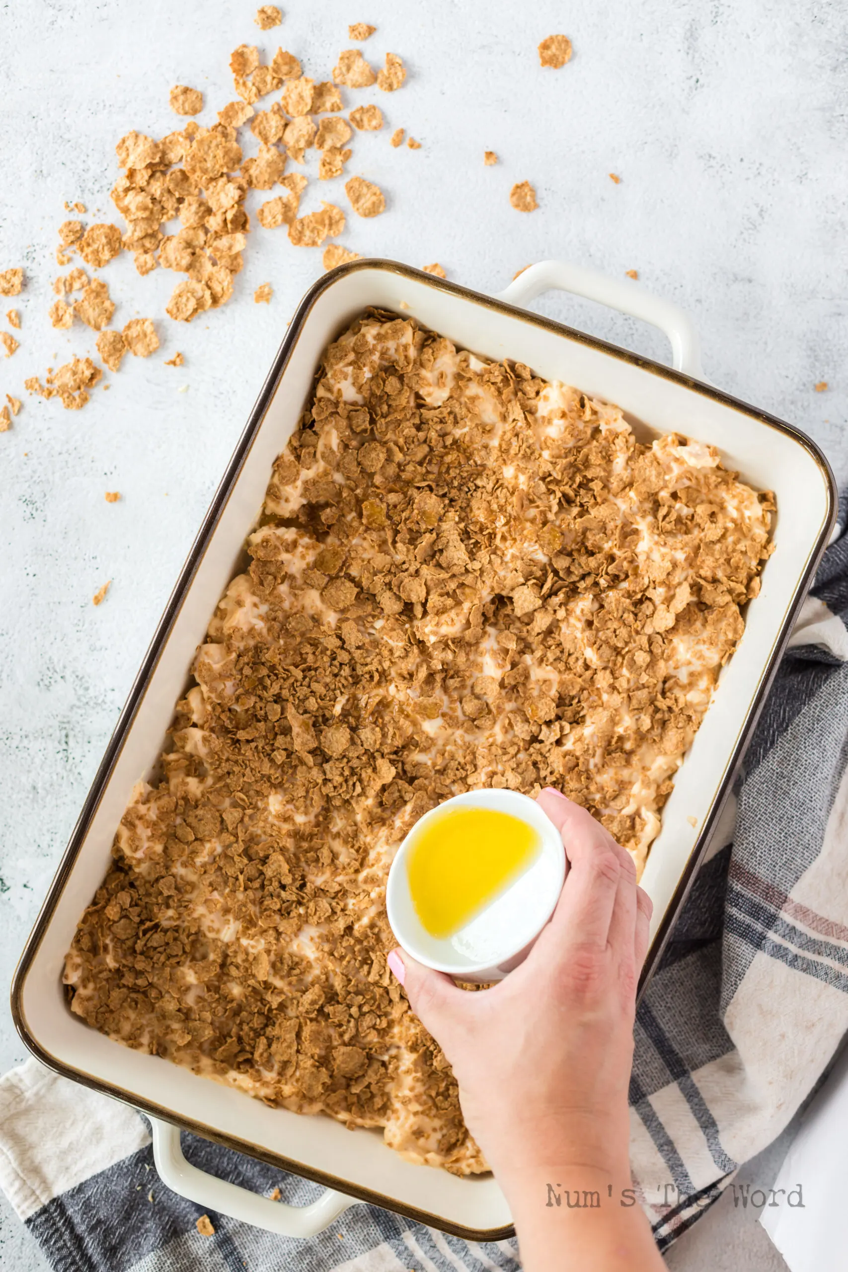 cornflakes added to the top of the casserole with butter being drizzled over it.