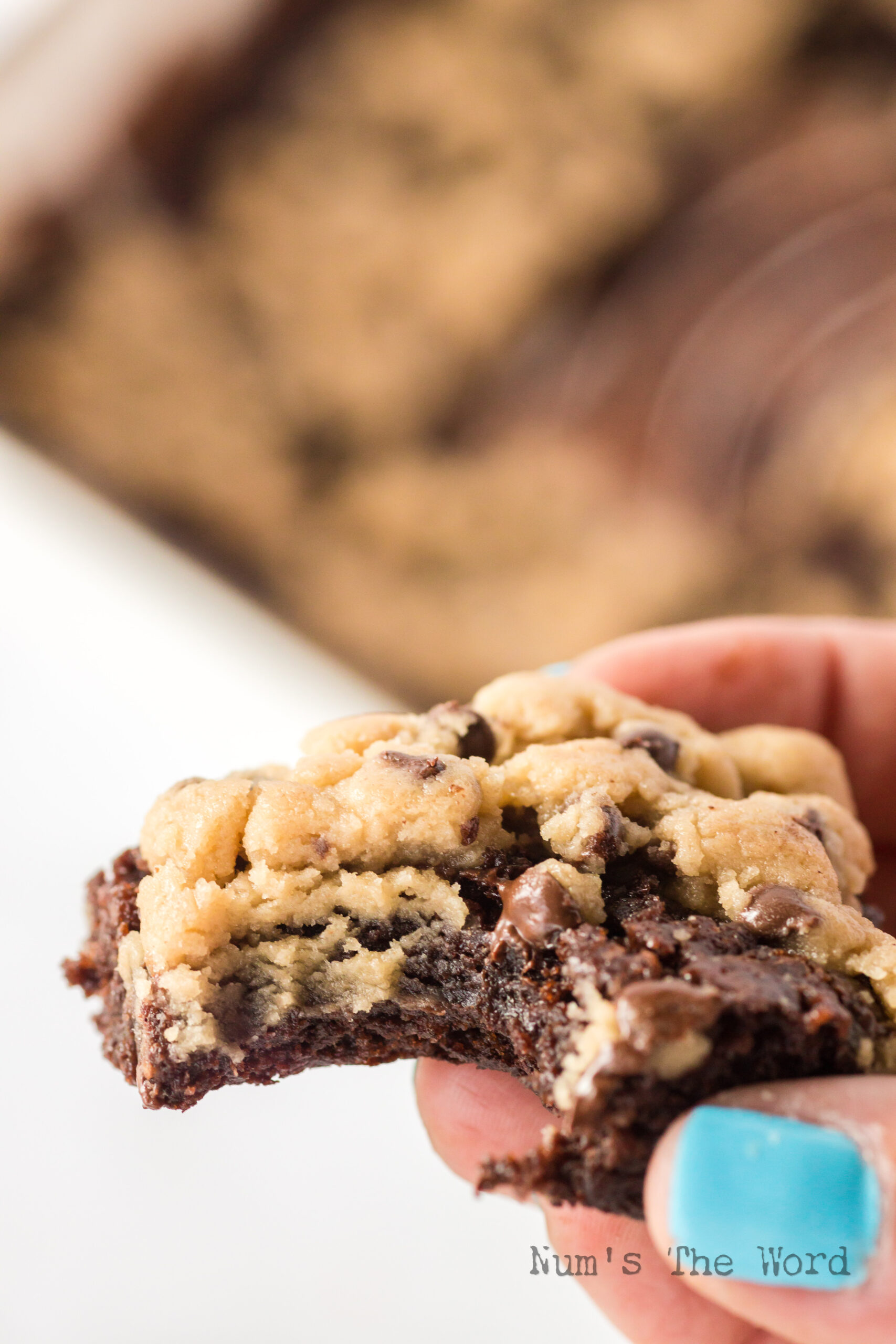 hand holding a cookie dough brownie with a bite removed