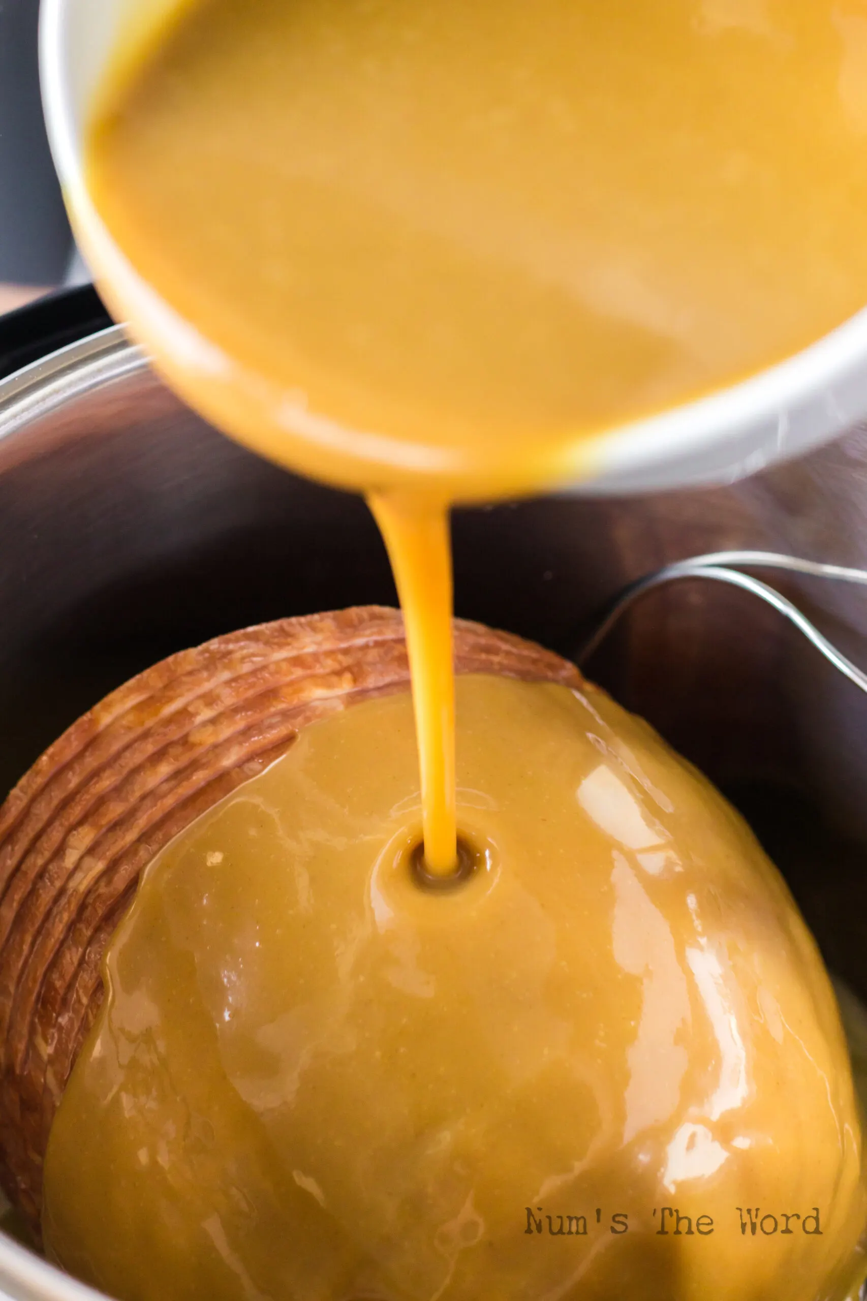 Ham cooked with glaze removed and cooked to create a honey mustard gravy. Gravy being poured over ham