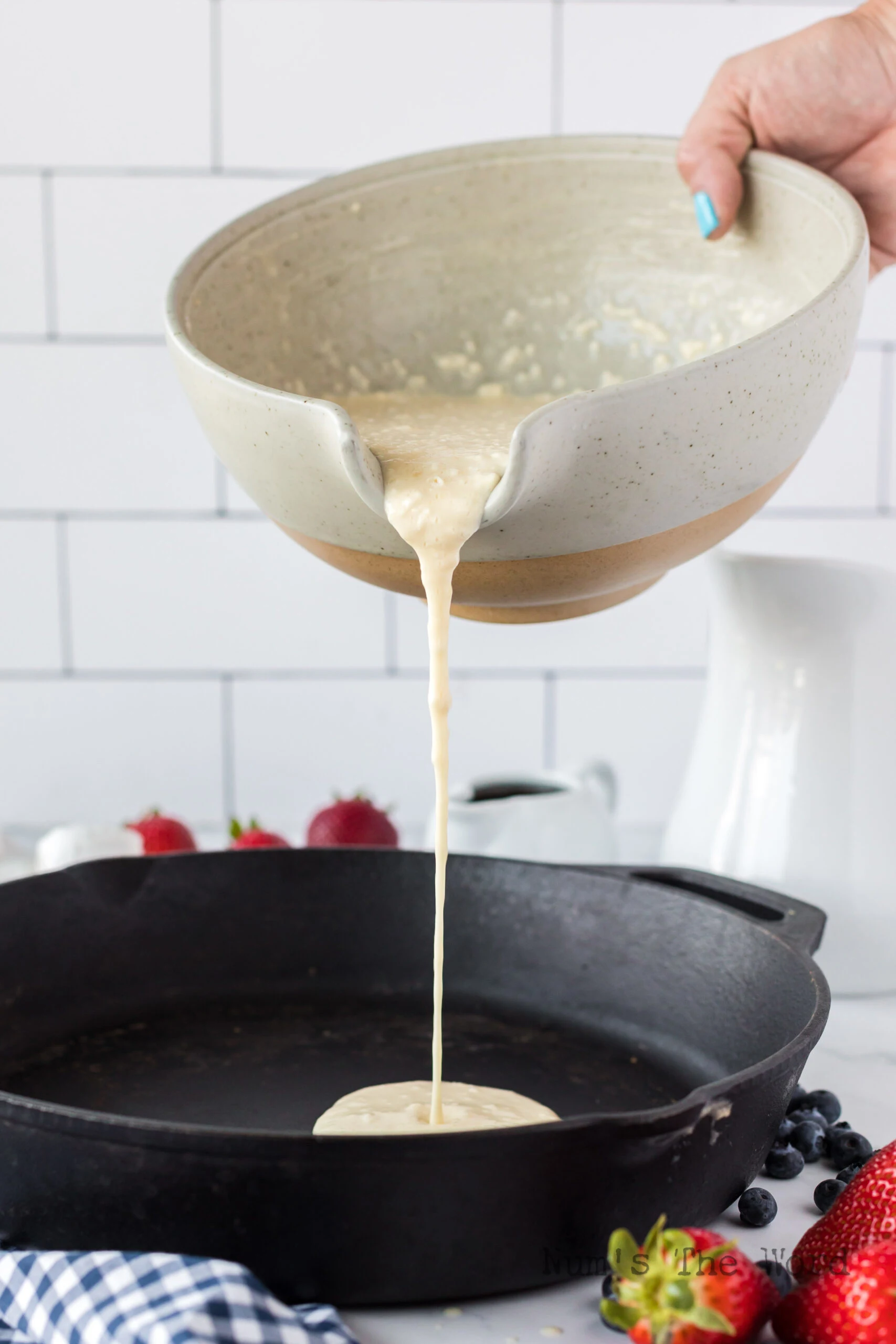 pancake mix being poured into a cast iron skillet