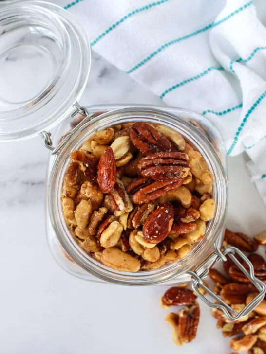 cooled spicy candied mixed nuts in an air tight jar with lid open