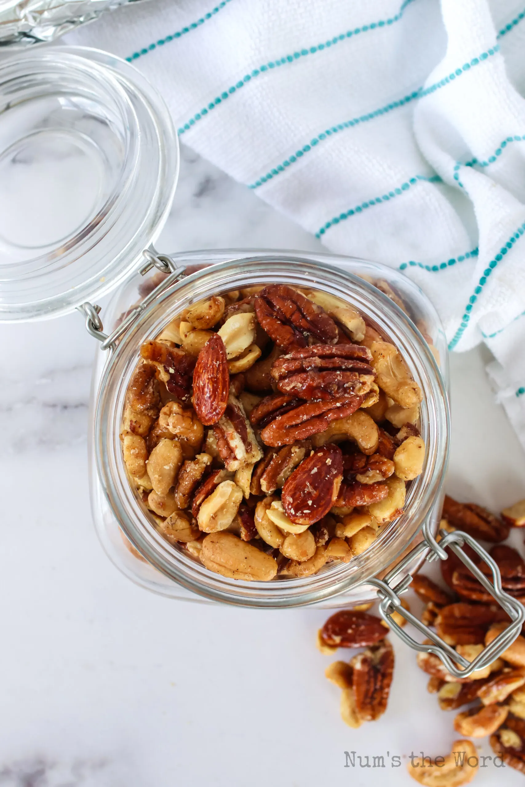 cooled spicy candied mixed nuts in an air tight jar with lid open