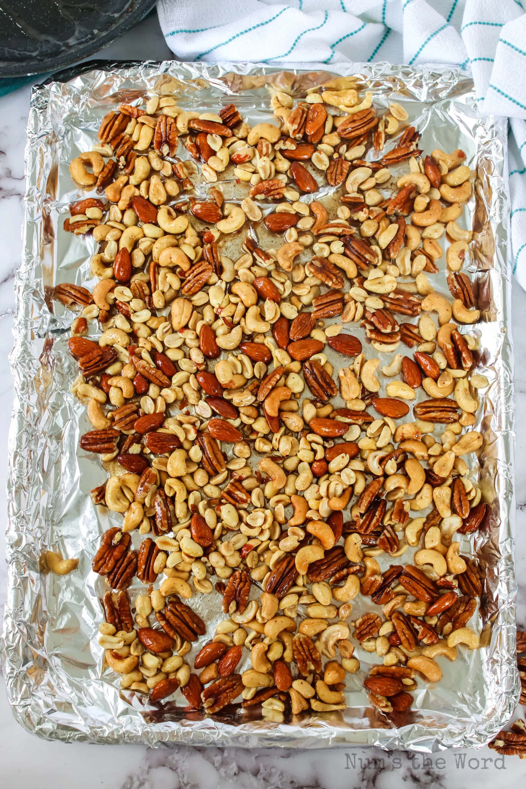 zoomed out image of coated mixed nuts on cookie sheet