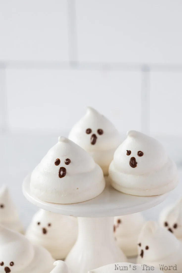 cute meringue ghosts on cake platter and all around, ready to serve