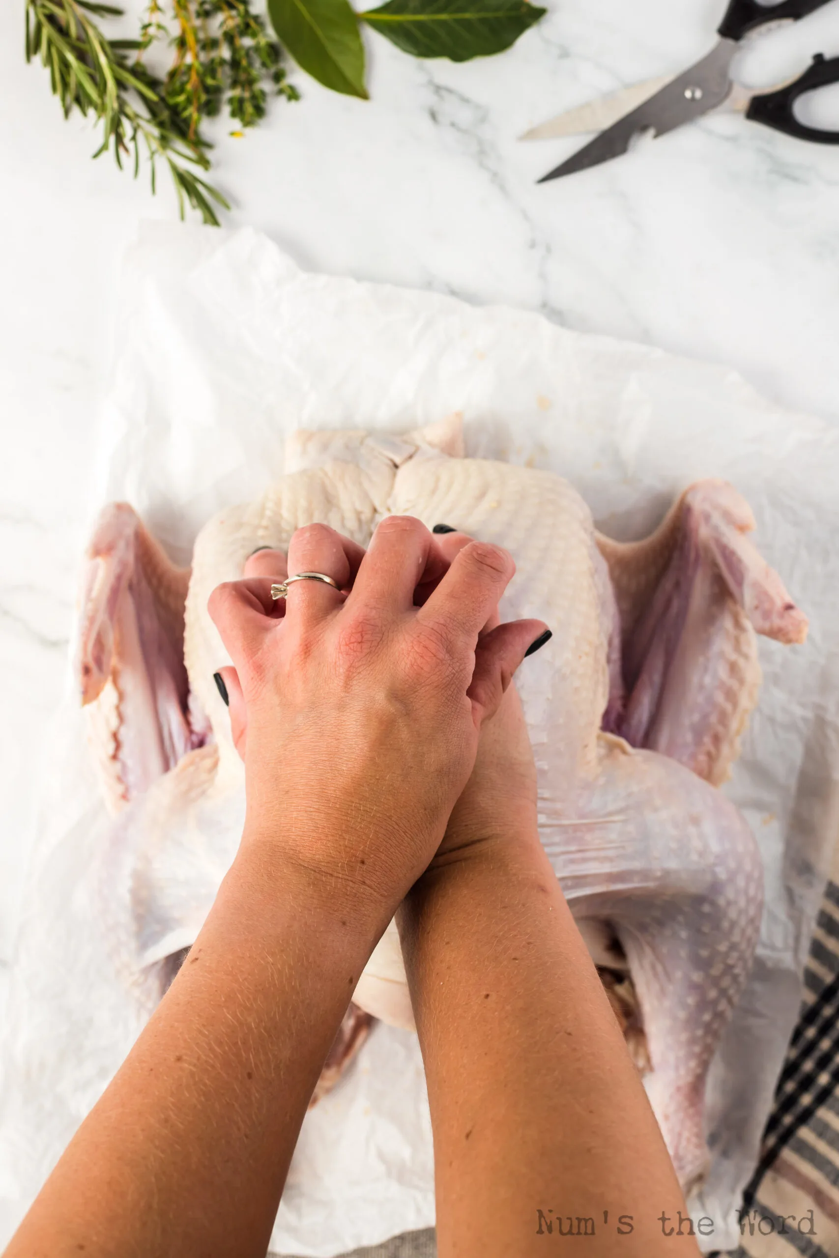 Hands breaking the breast bone to flatten turkey