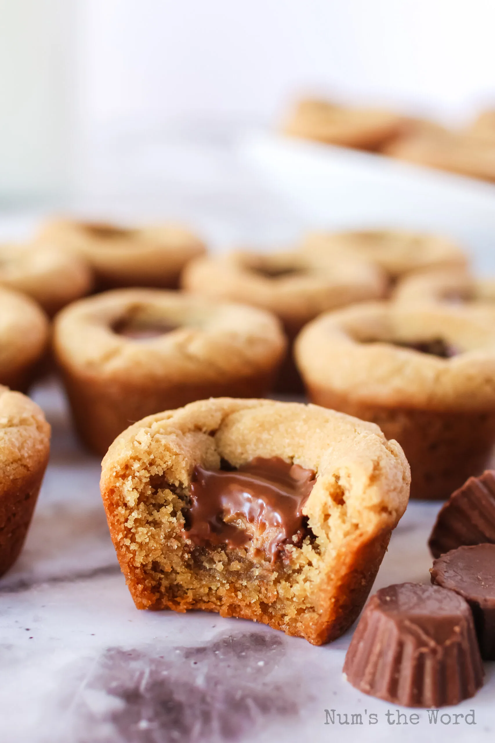 Peanut Butter Cookie Cups laid out on counter. Front cookie cup has a bite removed