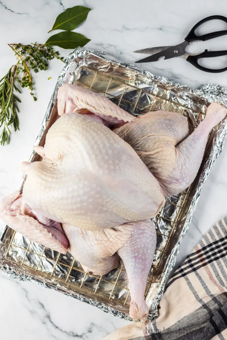 turkey on cooling rack above cookie sheet, ready to be put into the oven