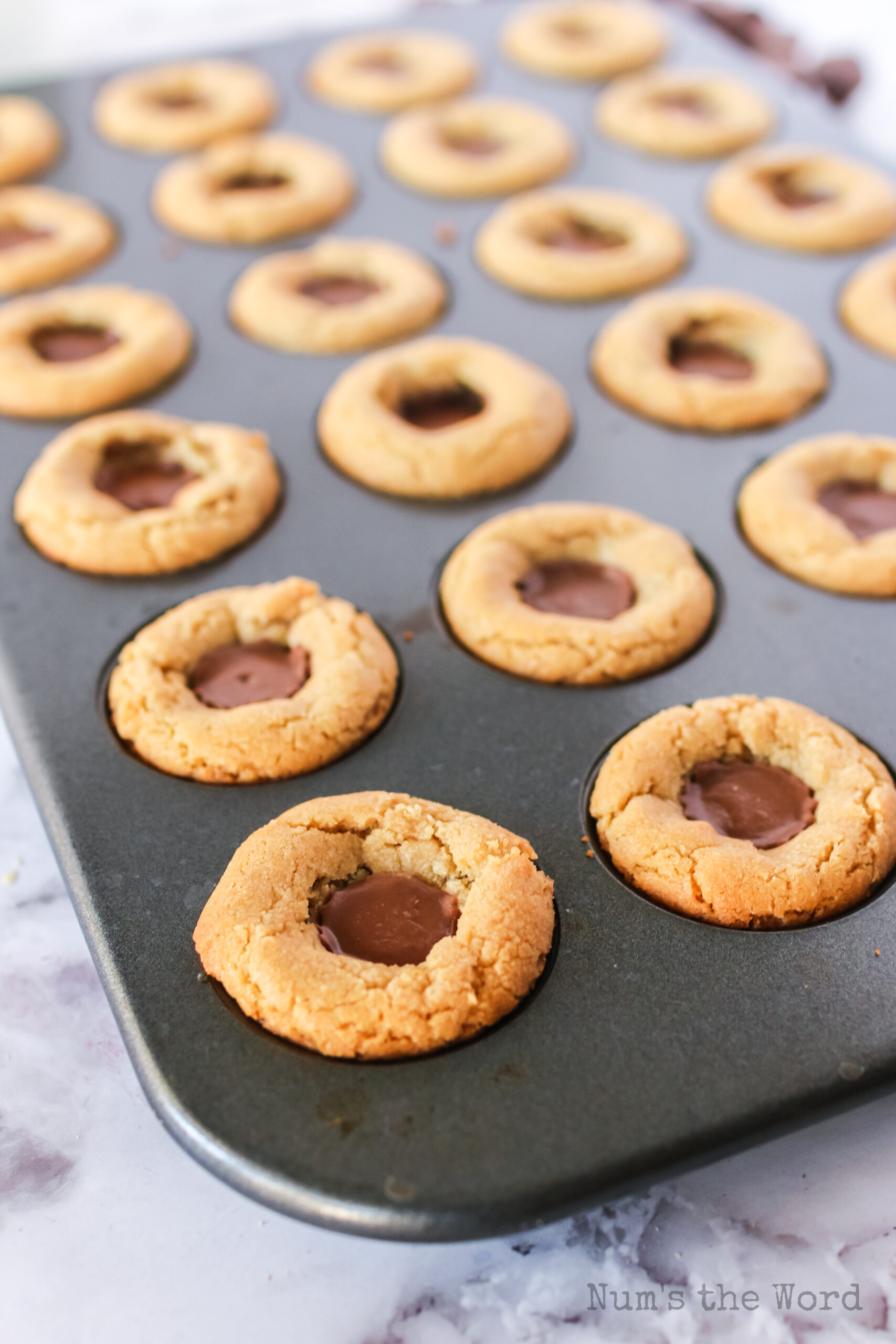 Baked peanut butter cookie cups in pan ready to pop out and eat