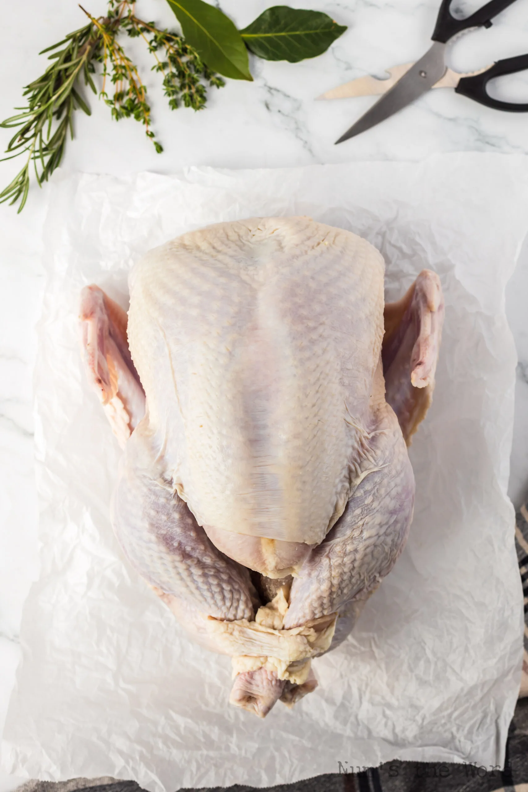 Opened turkey laid out on parchment paper, breast up