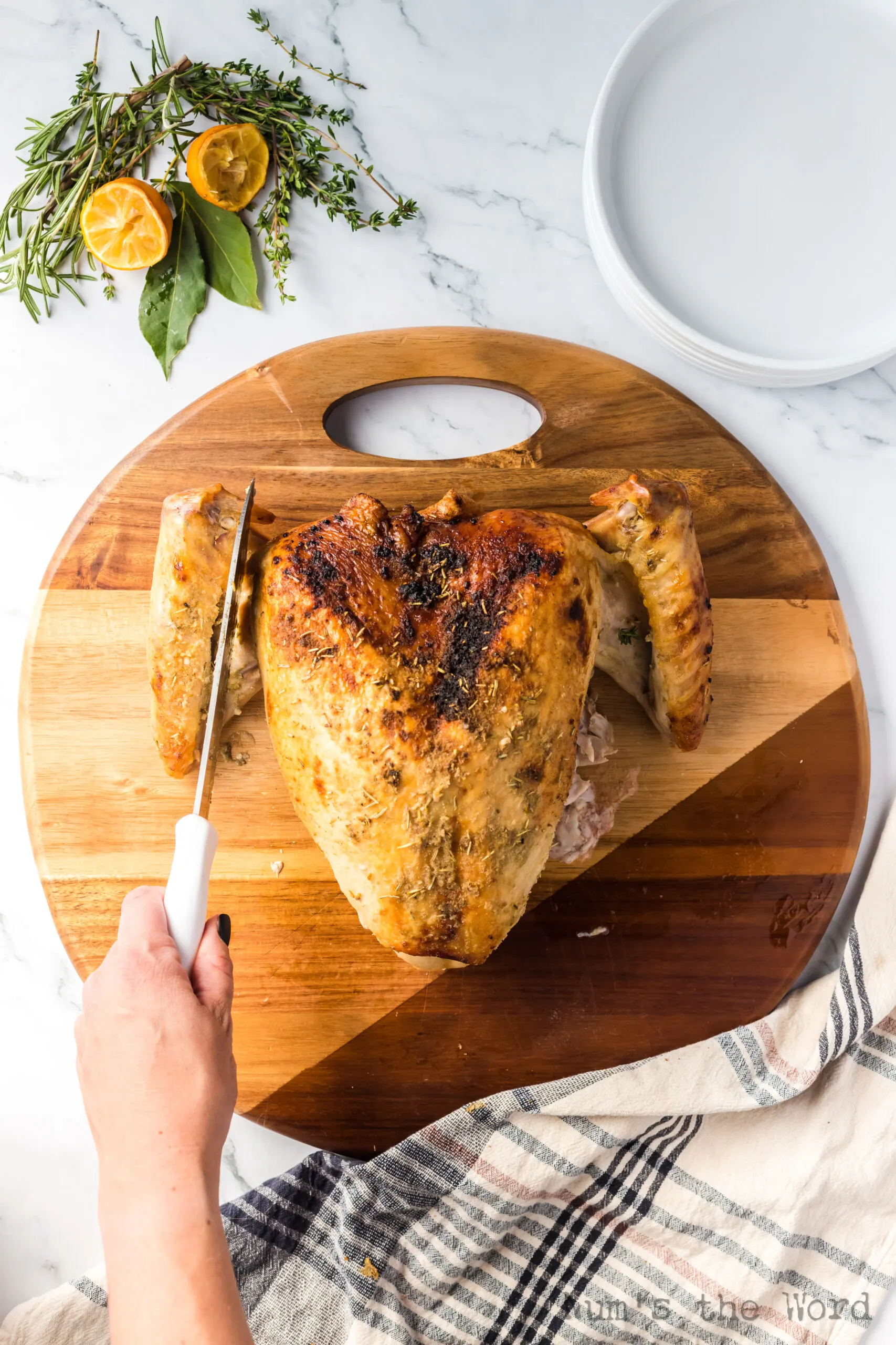 photo of turkey on platter with legs removed and knife showing how to cut the wings