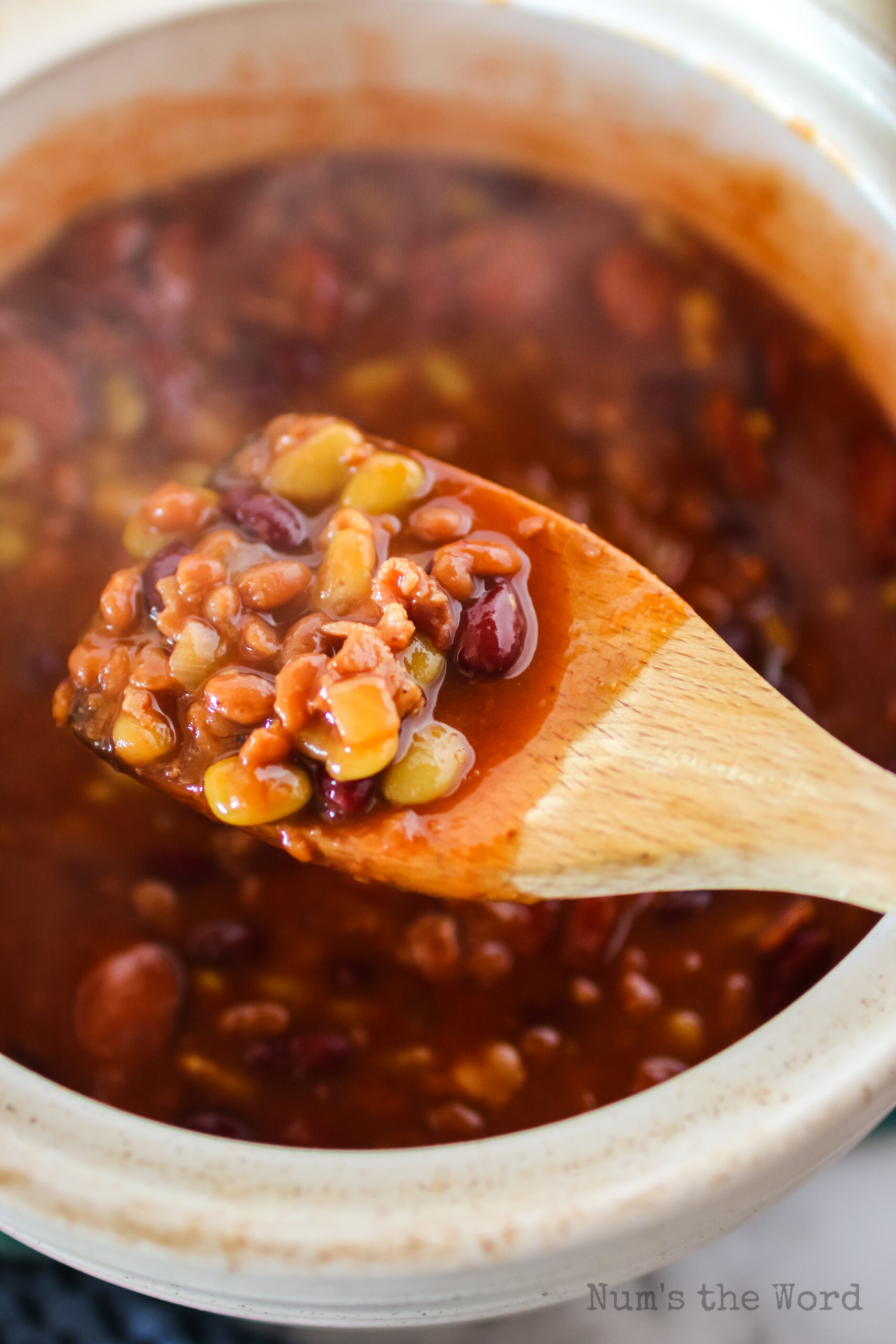 wooden spoon scooping out a portion of cowboy baked beans