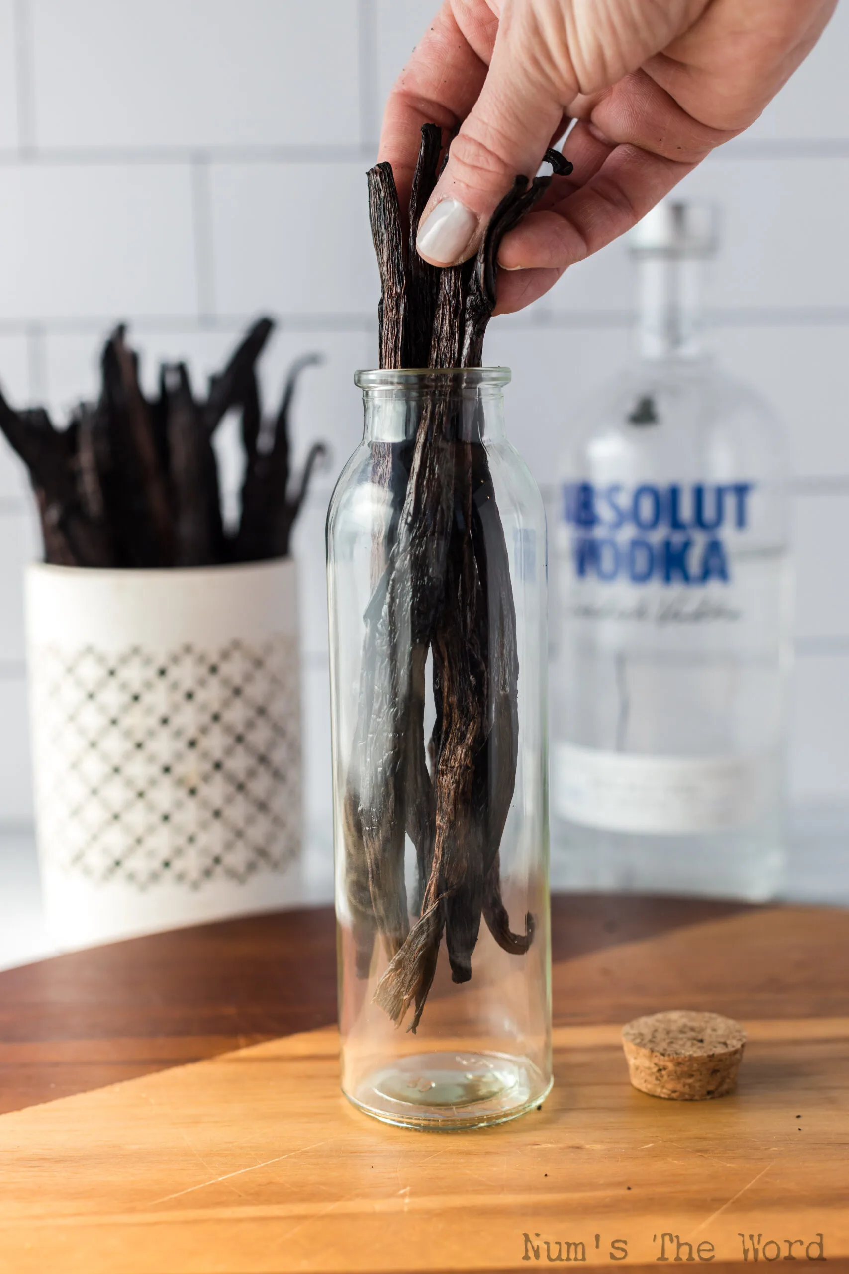 Hand placing the vanilla beans into a jar to brew into vanilla extract