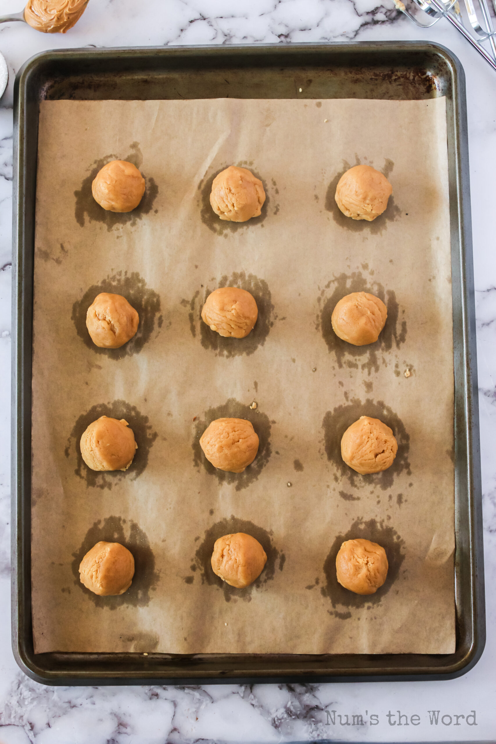 Peanut butter cookie dough balls unbaked on cookie sheet