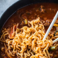 zoomed in image of soup in bowl with chop sticks pulling noodles