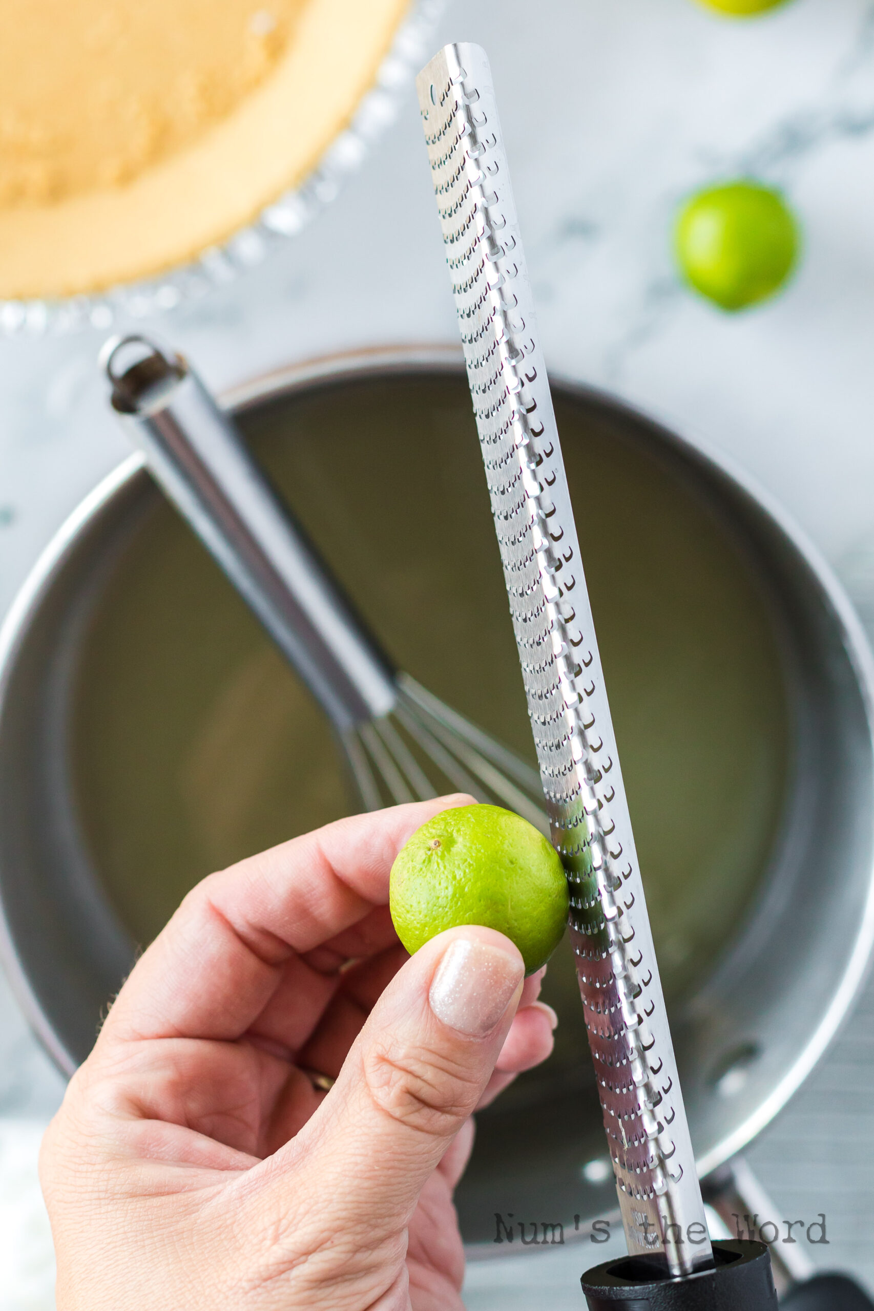 cooked water, sugar and gelatin in a bowl with key limes being zested into the bowl.