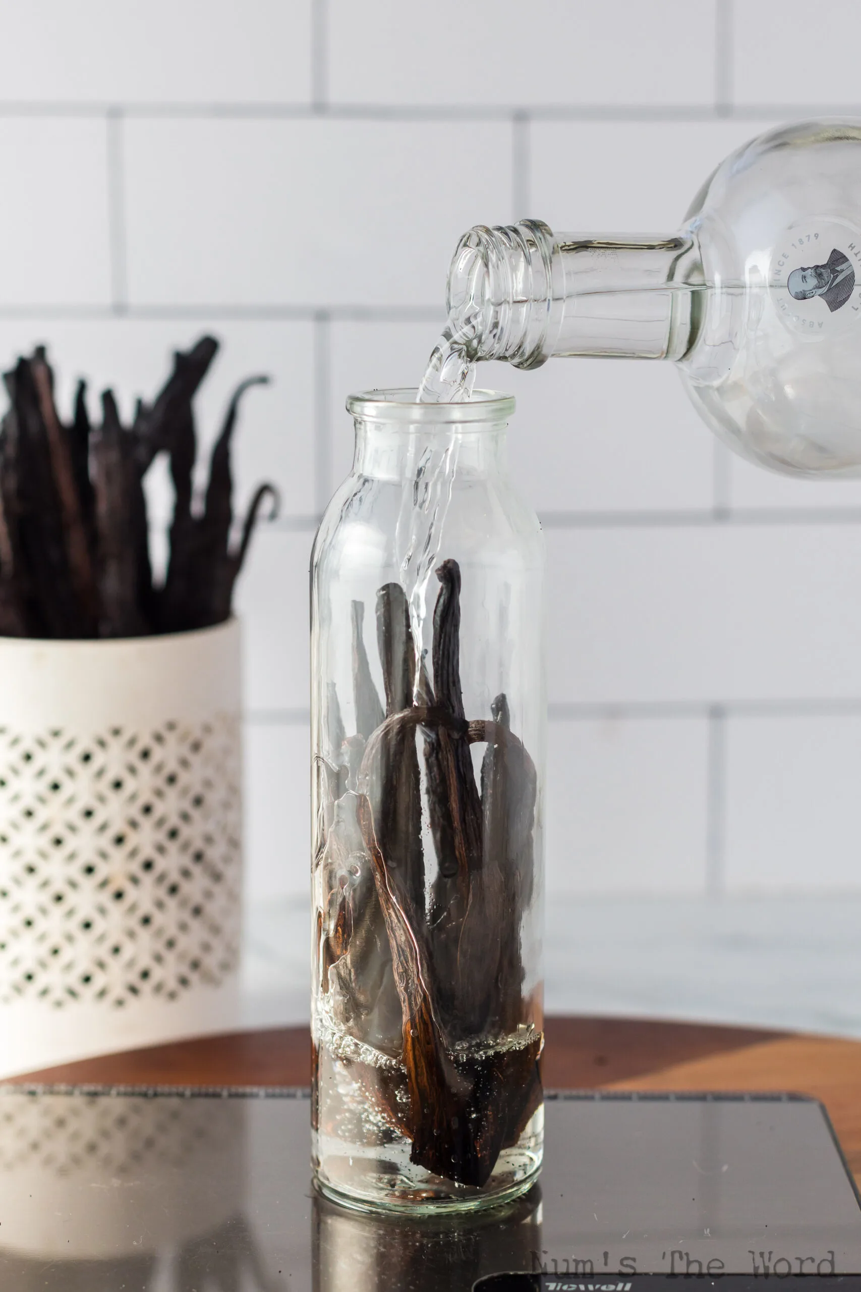 Pouring alcohol into the vanilla bean bottle to cover the beans