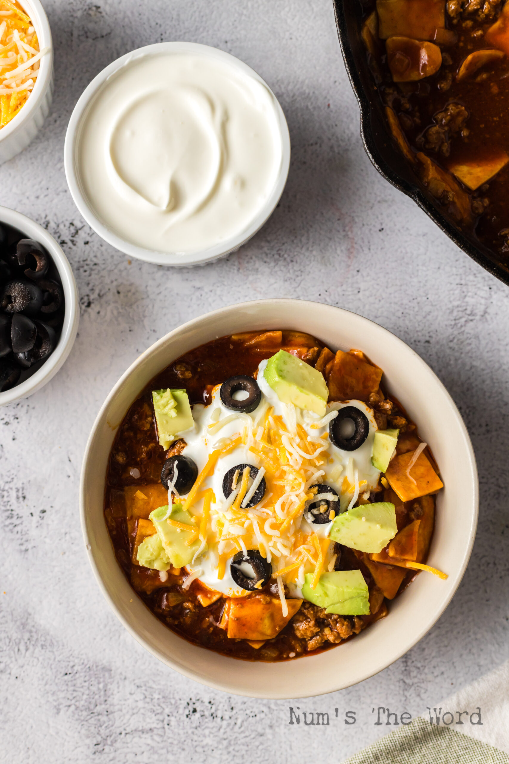 Beef enchilada skillet bowl topped with avocado, sour cream olives and cheese
