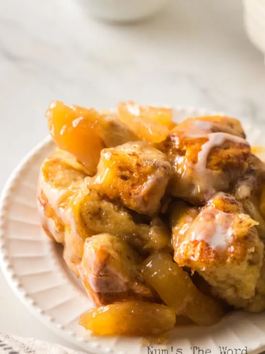zoomed in image of cinnamon roll casserole with apples on plate.