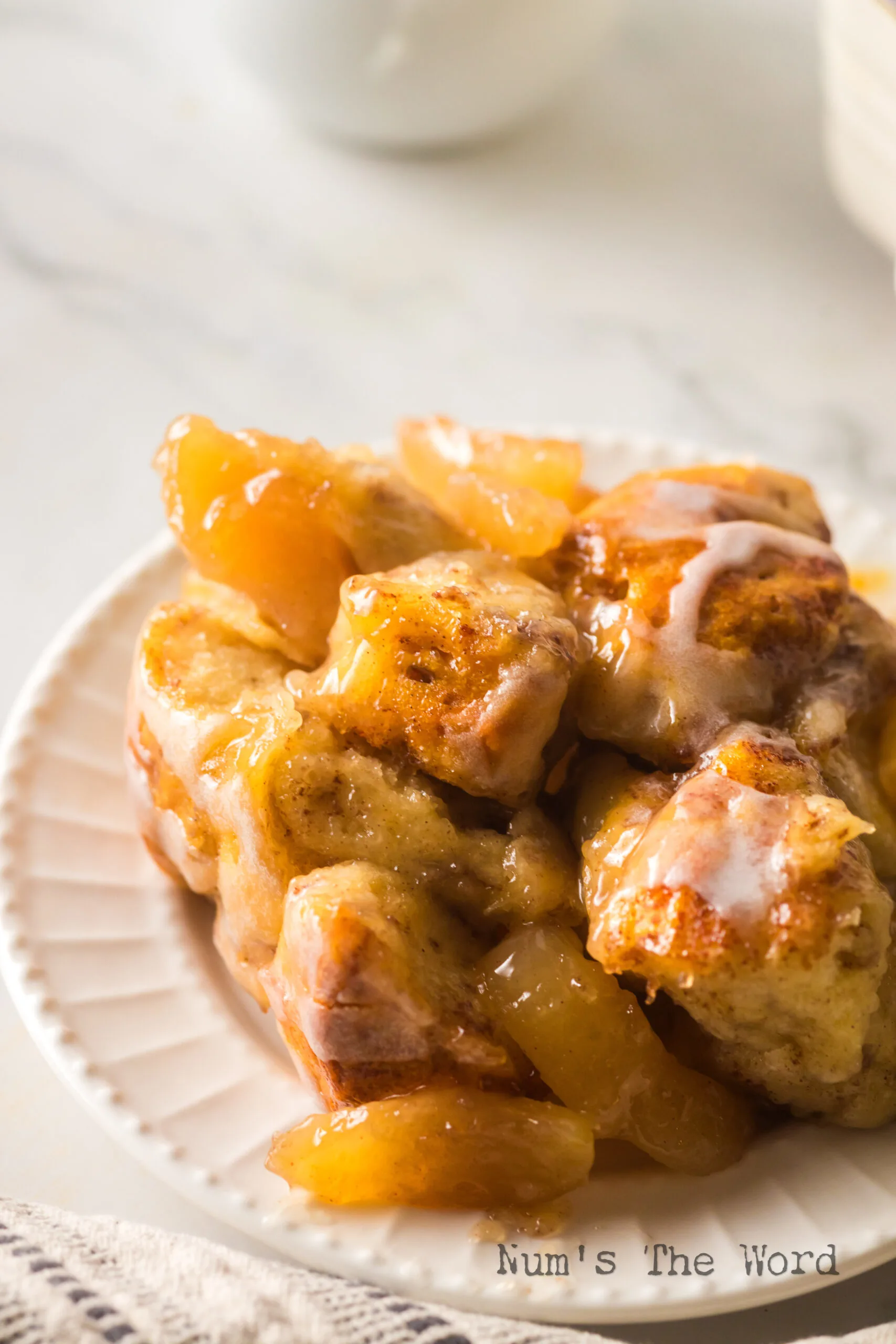 zoomed in image of cinnamon roll casserole with apples on plate.