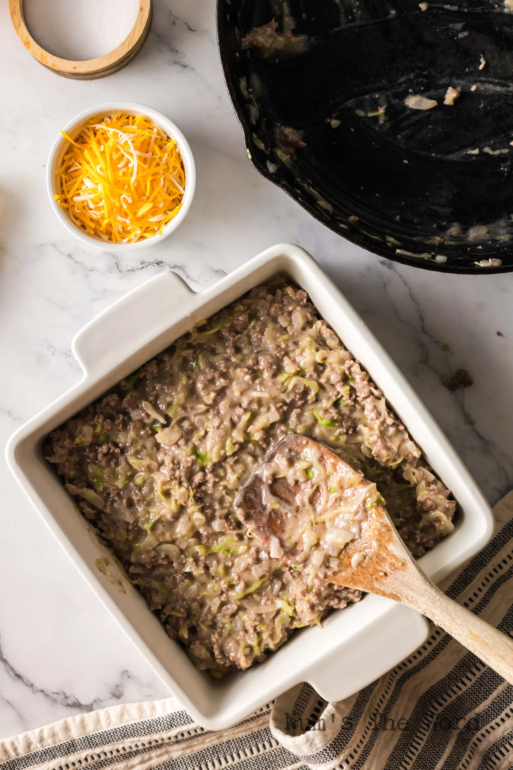 Beef mixture being placed in casserole dish on top of crescent roll dough.