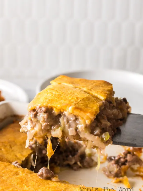A slice of casserole being removed from pan.