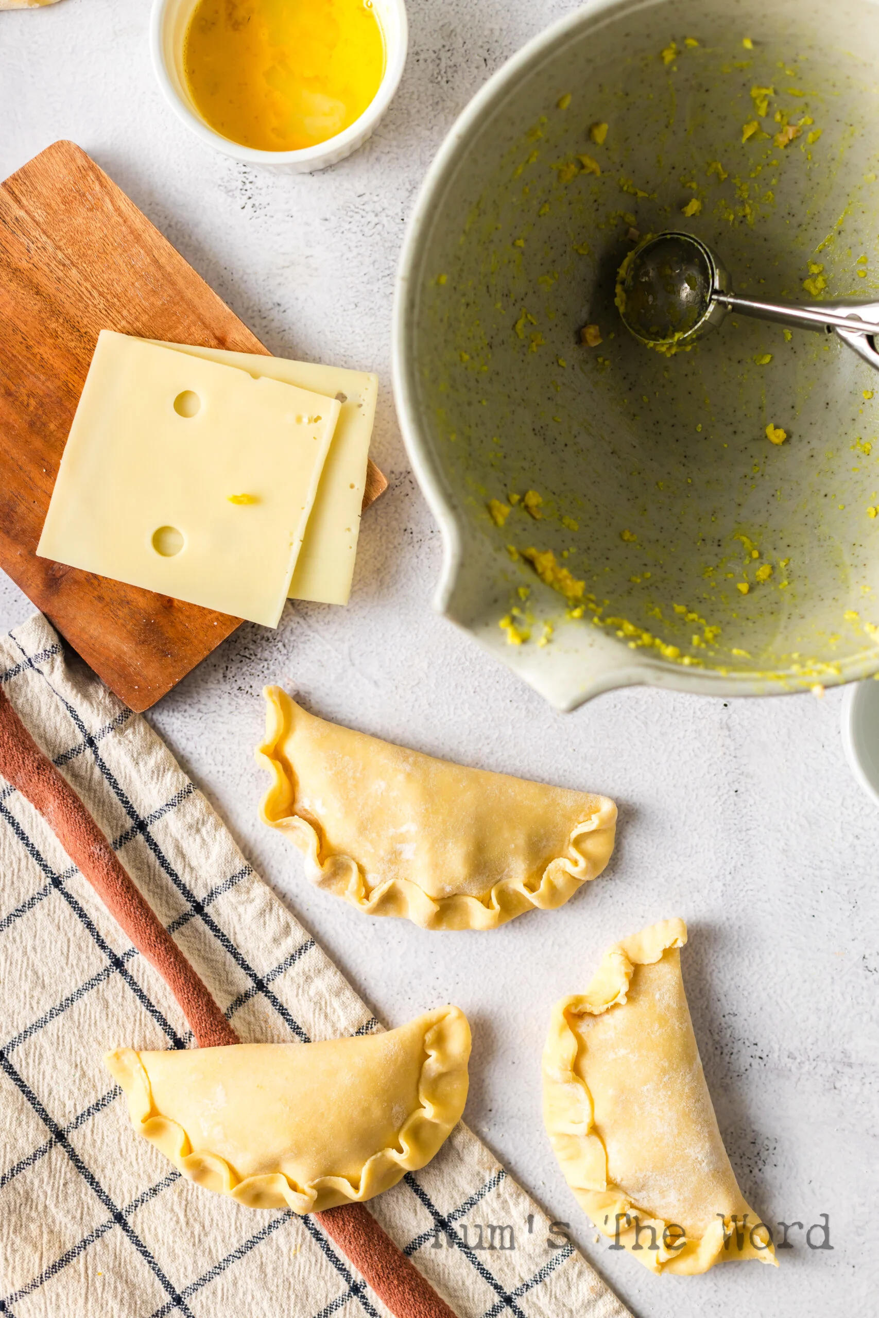 Folded and crimped empanadas on counter ready to bake.