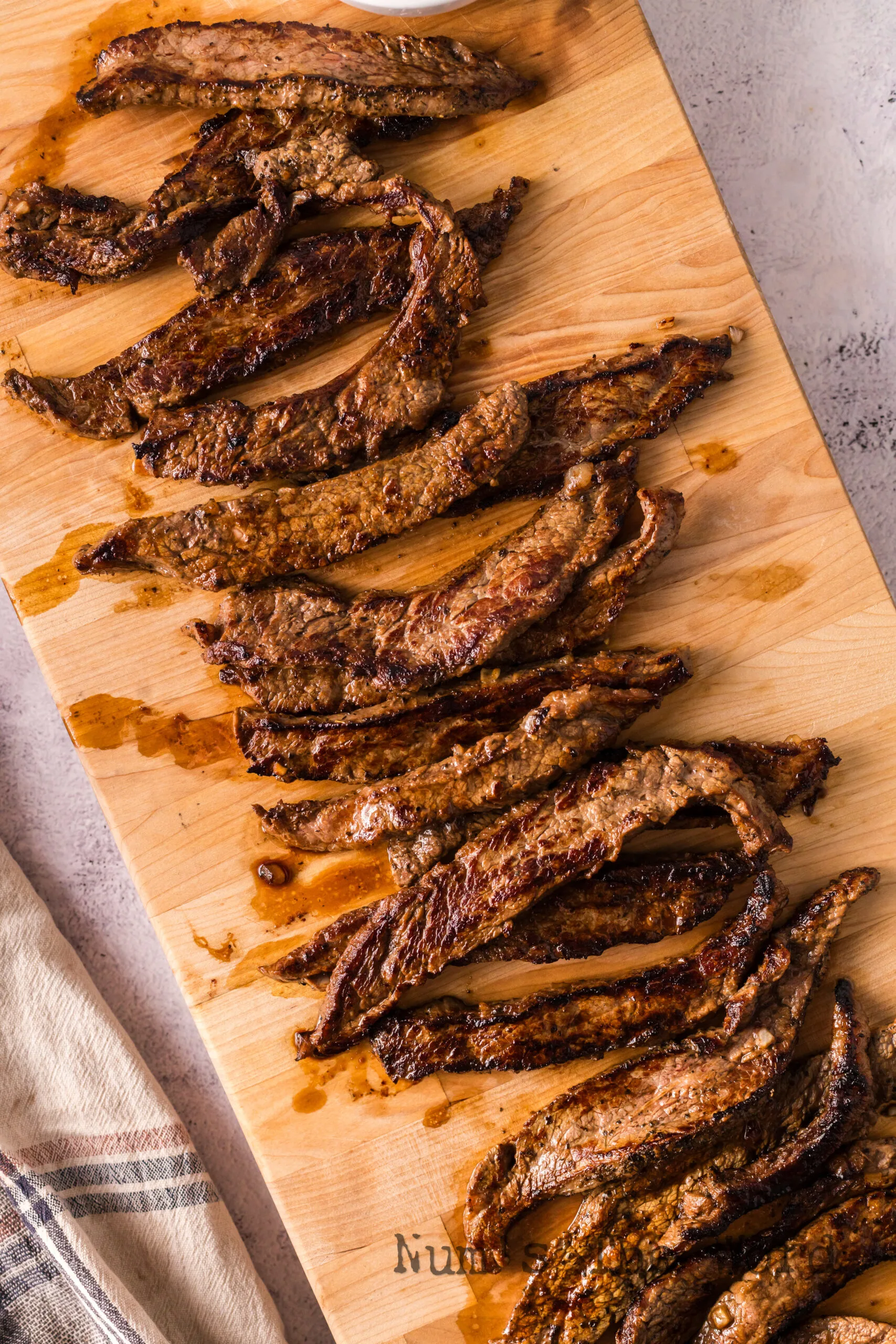 zoomed out image of cooked flank steak on cutting board.