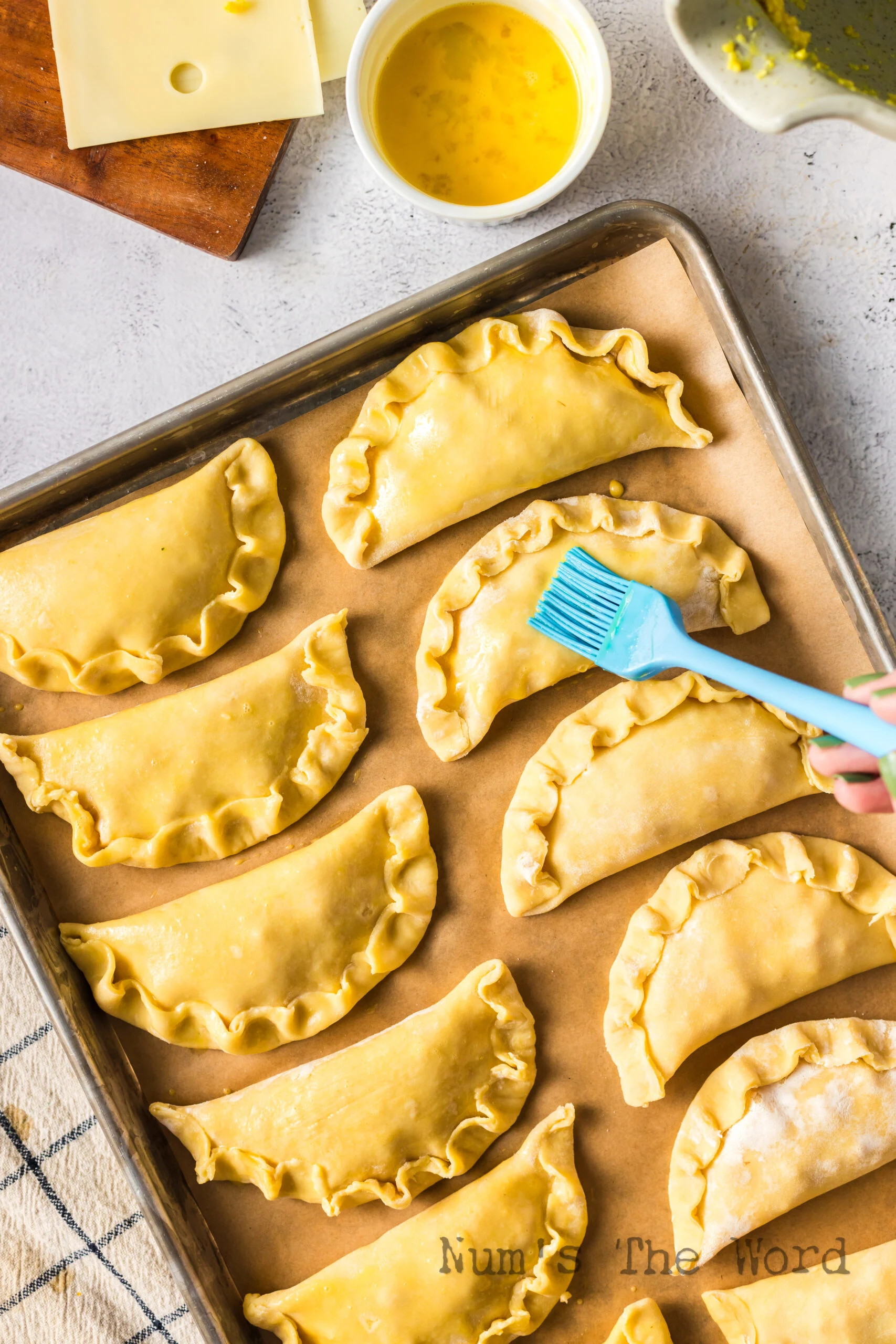 Empanadas placed on a baking sheet with egg was being brushed on top