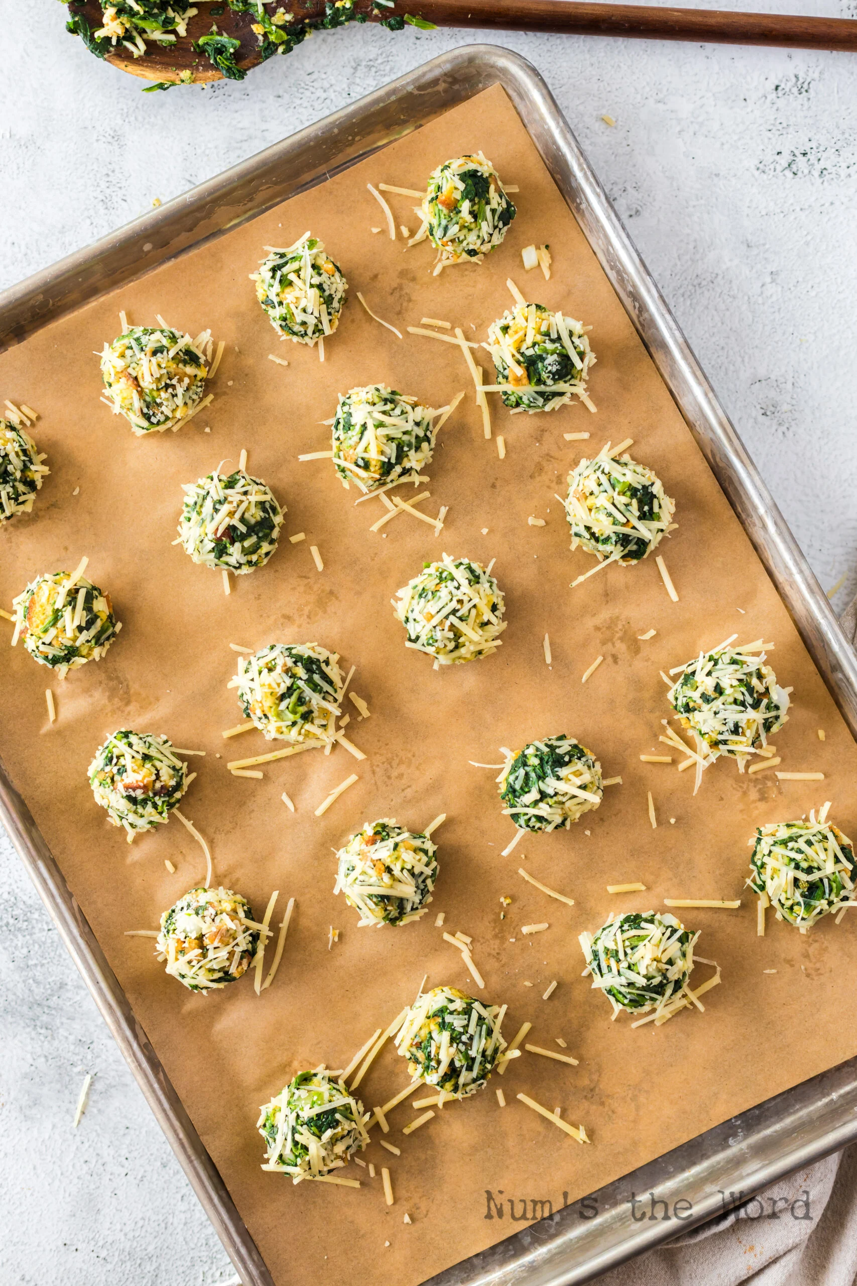unbaked spinach balls laid out on cookie sheet
