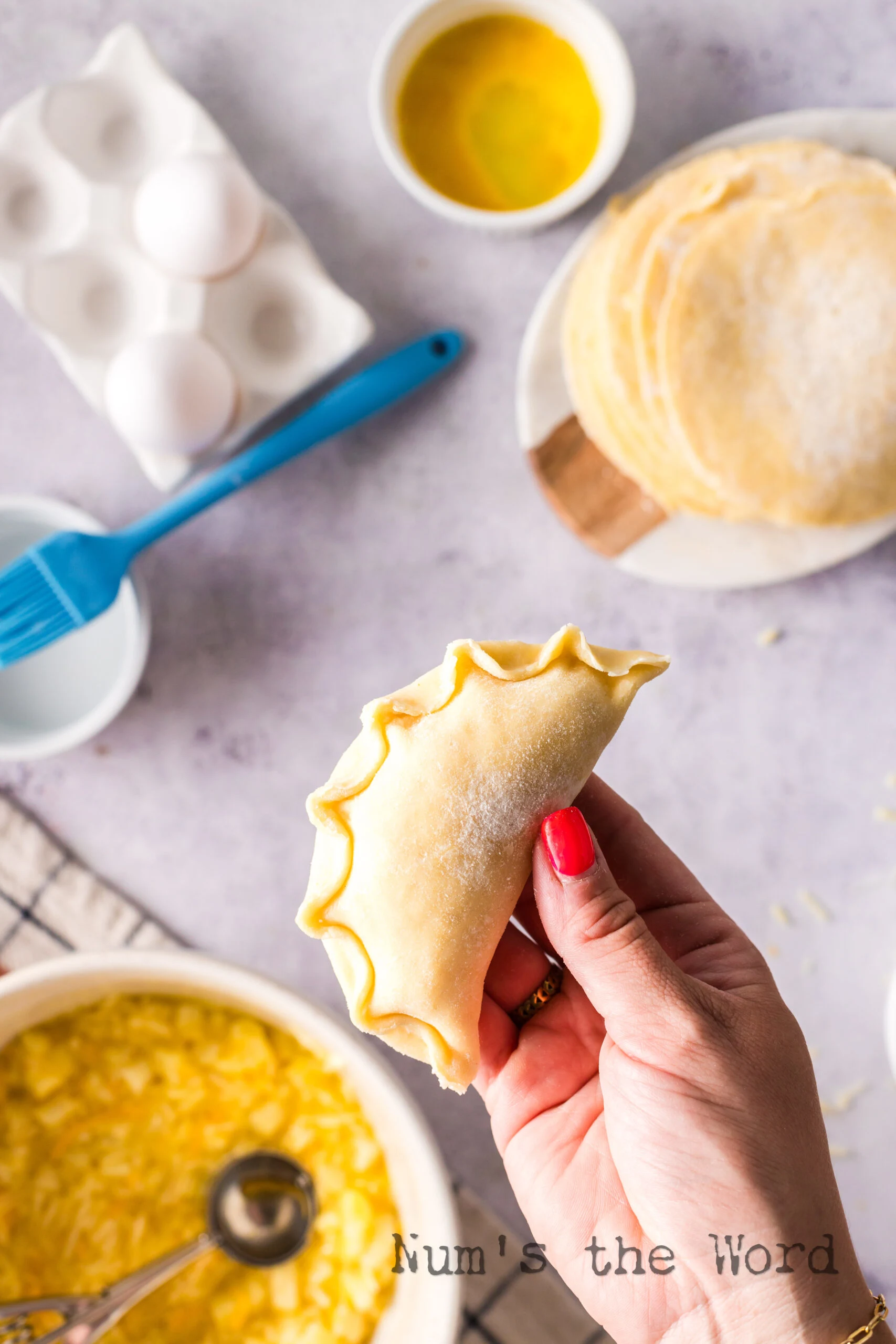 filled and sealed empanada, unbaked, held in a hand.