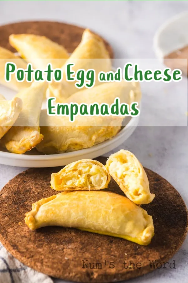 Main image for Potato Egg and Cheese Empanada recipe. empanadas on a platter in the background with two empanadas in front. One of the two are cut in half.