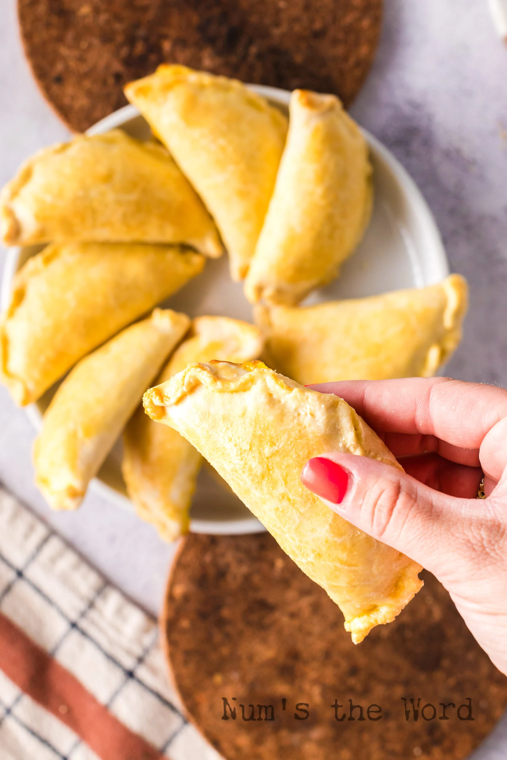 Hand holding a baked empanada, ready to eat.