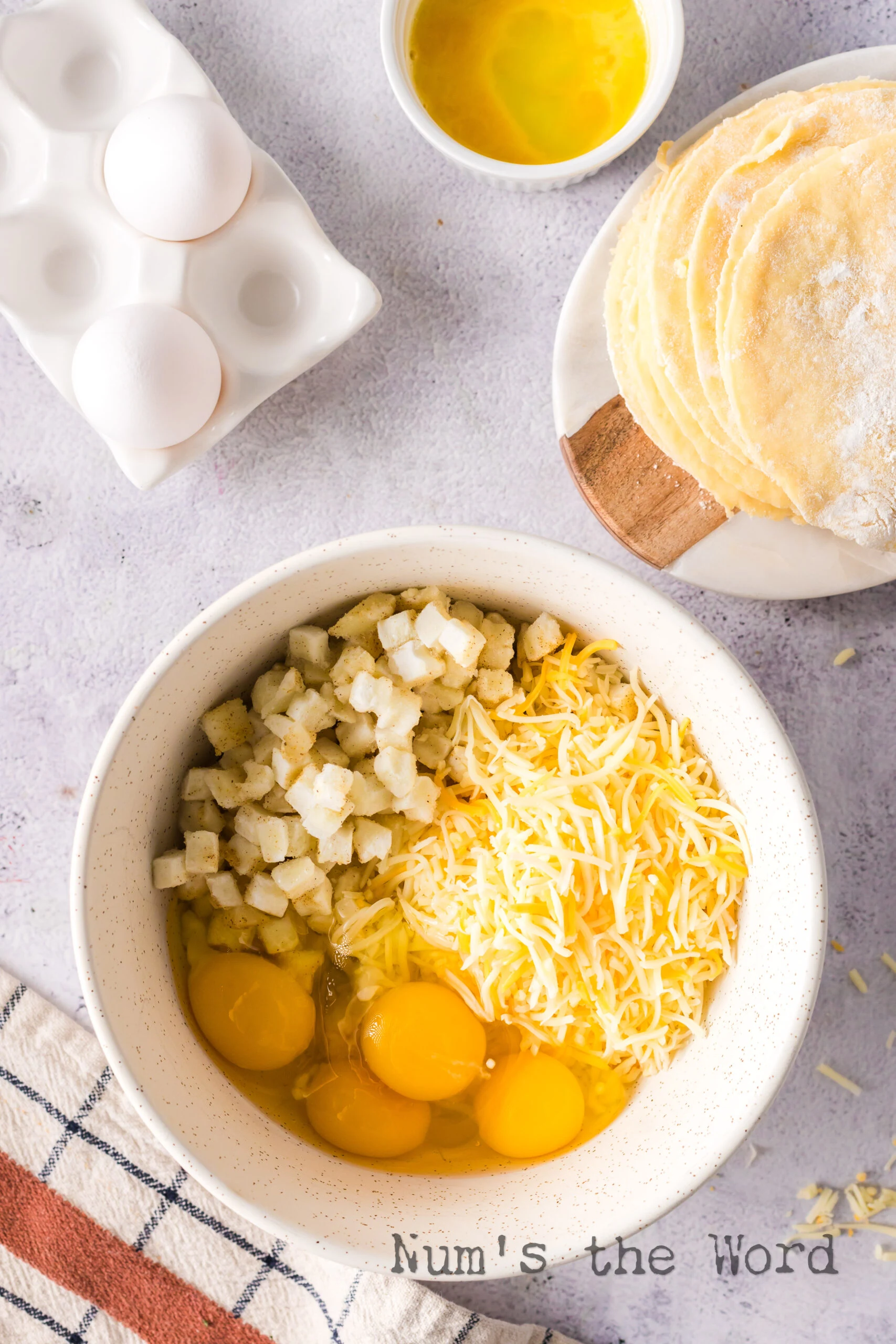 Hash brown potatoes, eggs and cheese in a bowl unmixed.
