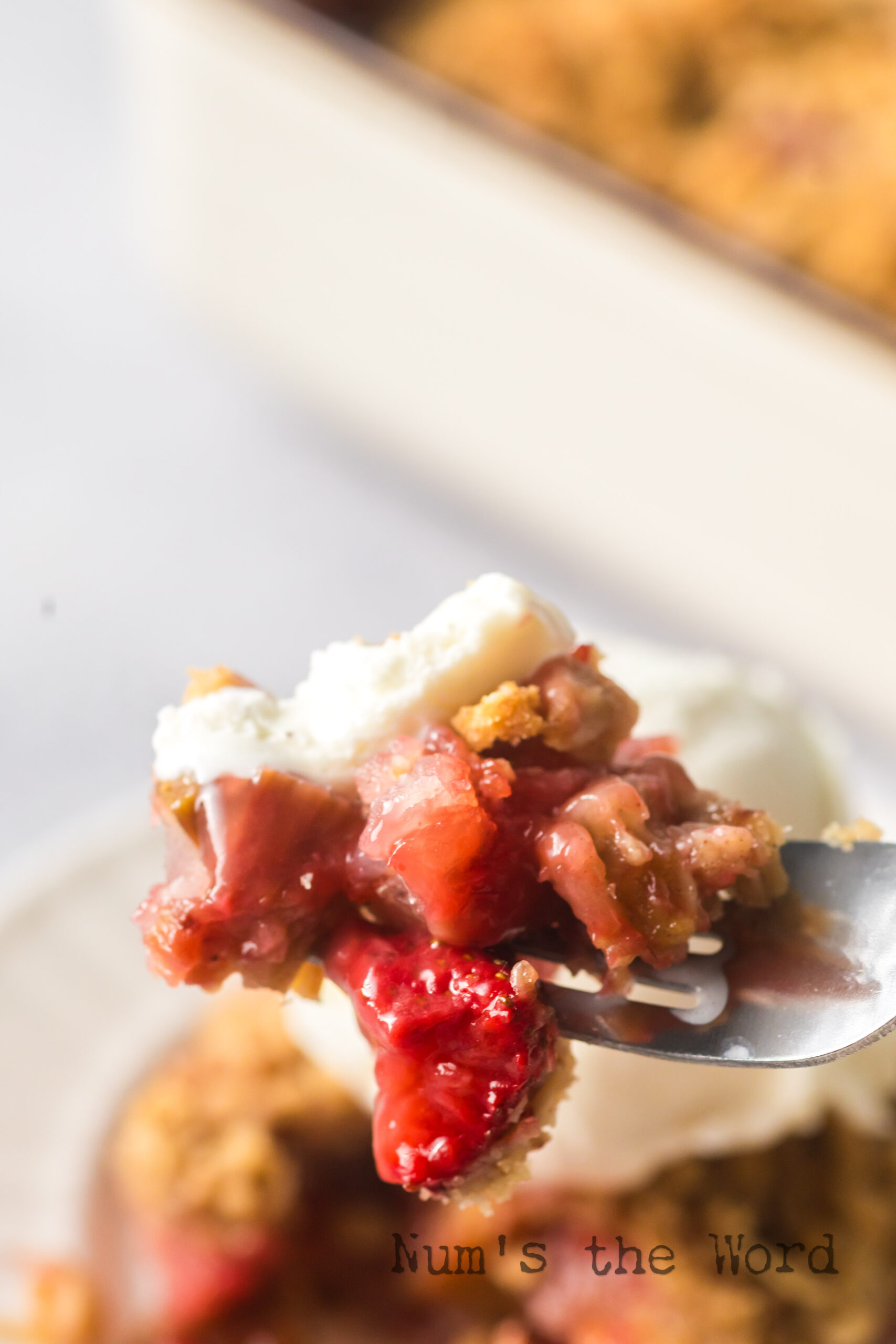 spoon scooping up a portion of fruit crisp with ice cream.