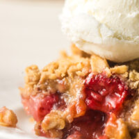 zoomed in image of a scoop of crisp on a plate with a scoop of vanilla ice cream next to it.