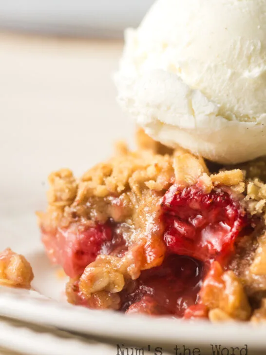 zoomed in image of a scoop of crisp on a plate with a scoop of vanilla ice cream next to it.
