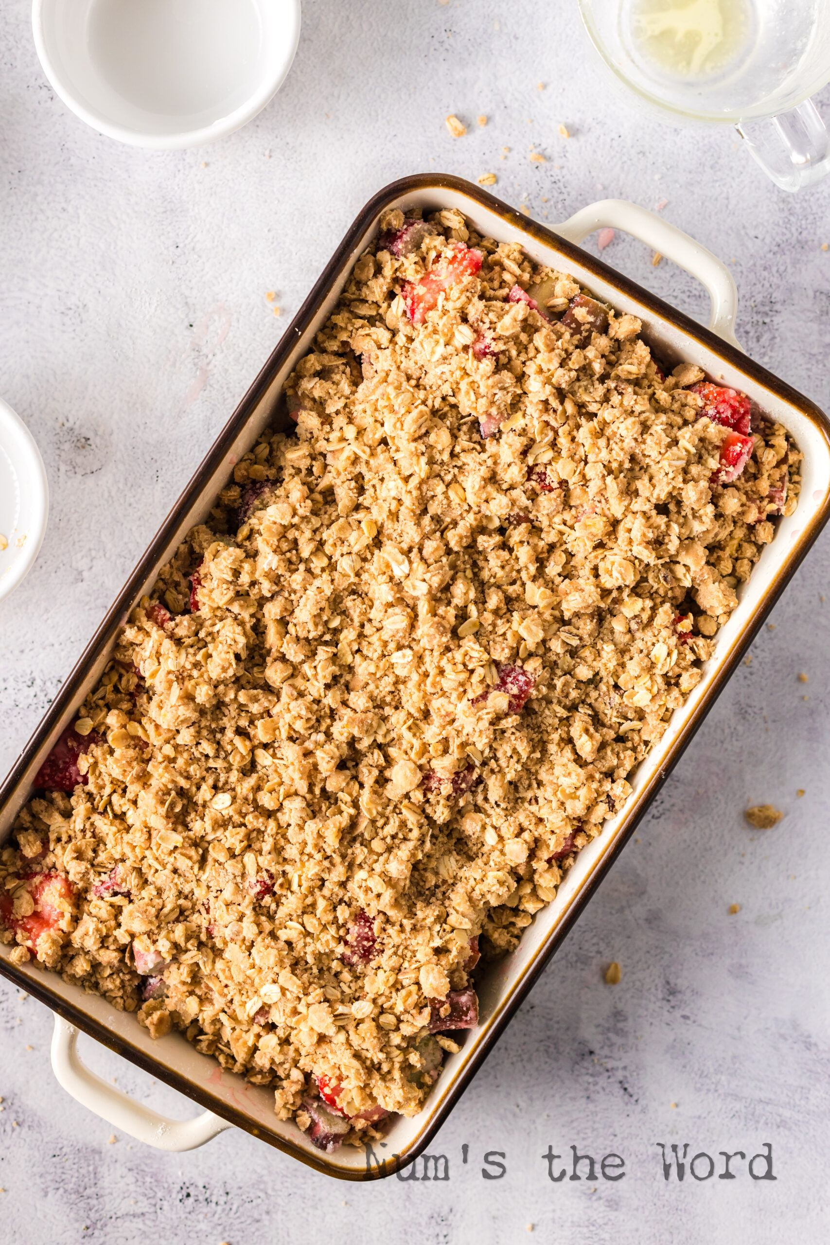 Crumble mixture spread out on top of strawberry rhubarb mixture in casserole dish.