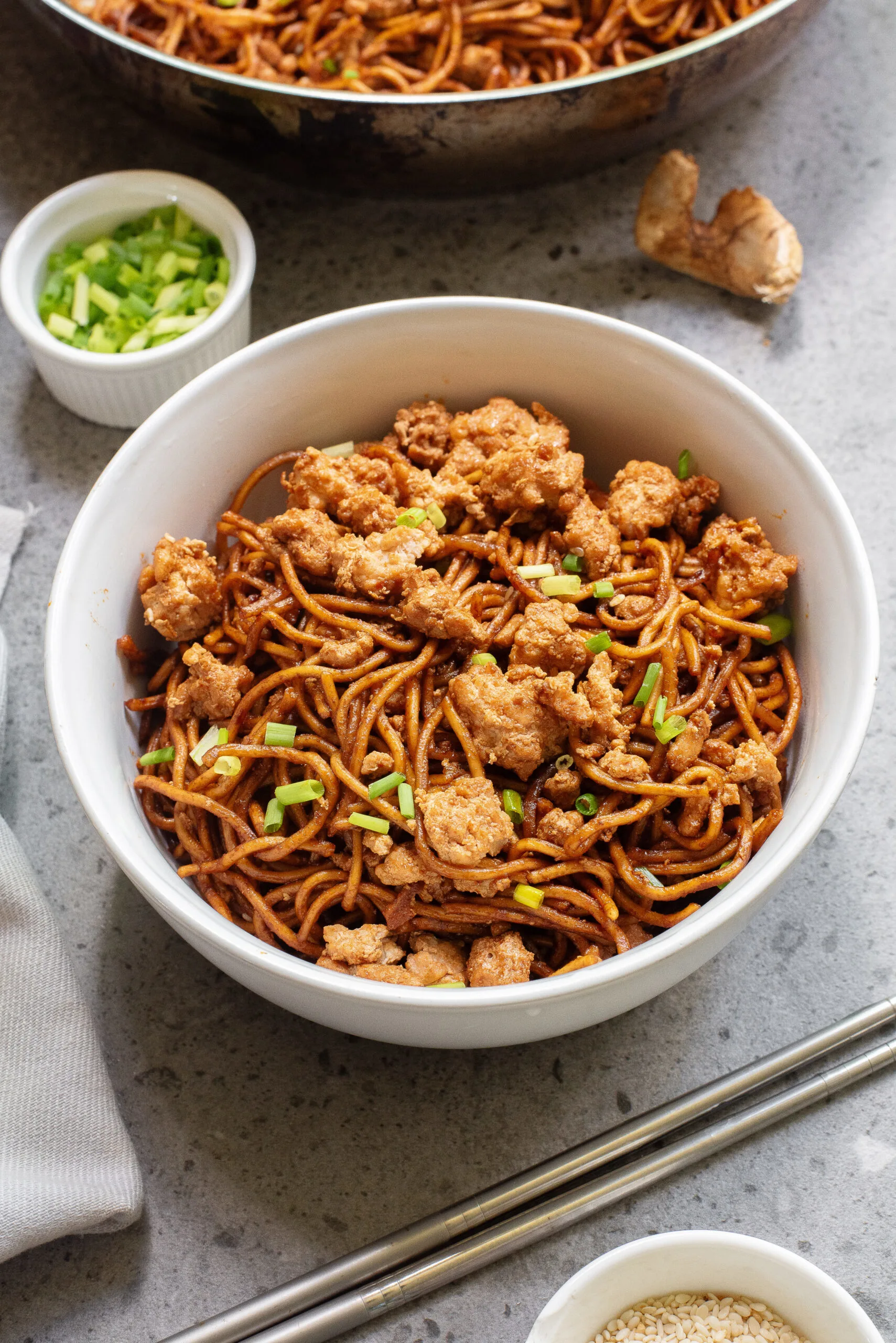 chicken and noodles in a bowl with chop sticks.