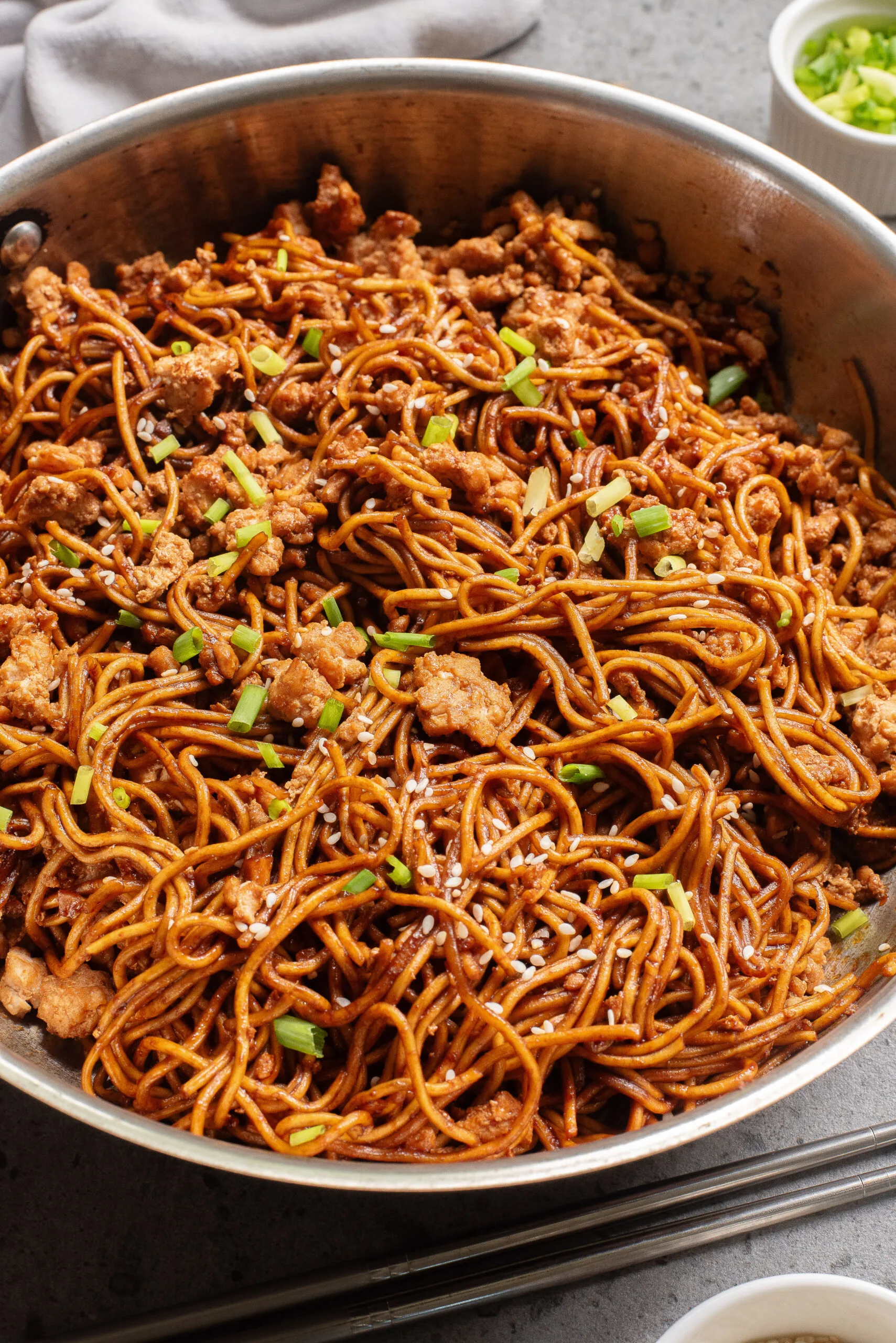 cooked chicken and noodles in pan with green onions.